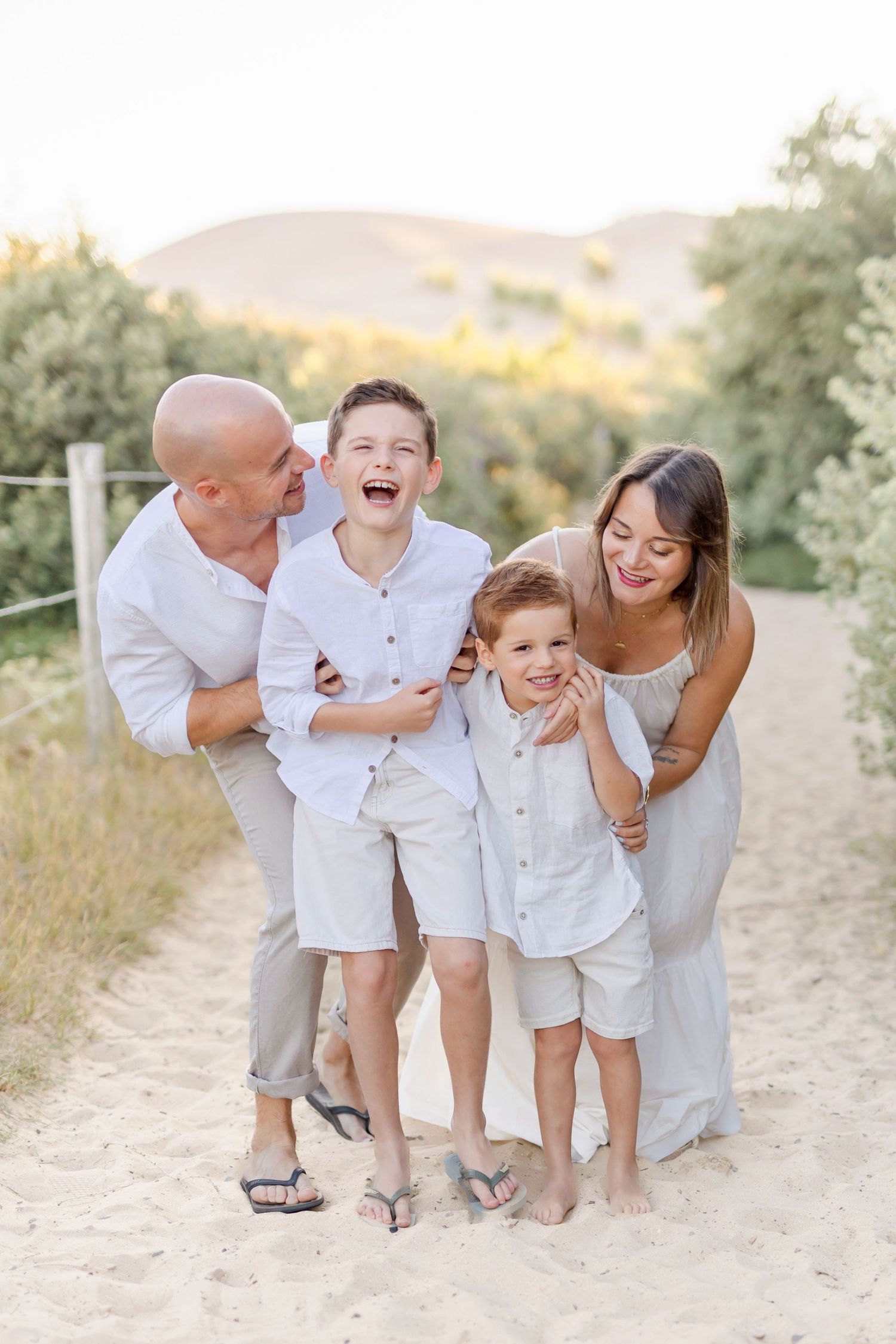 Joyful family moment captured on sandy path during golden hour.