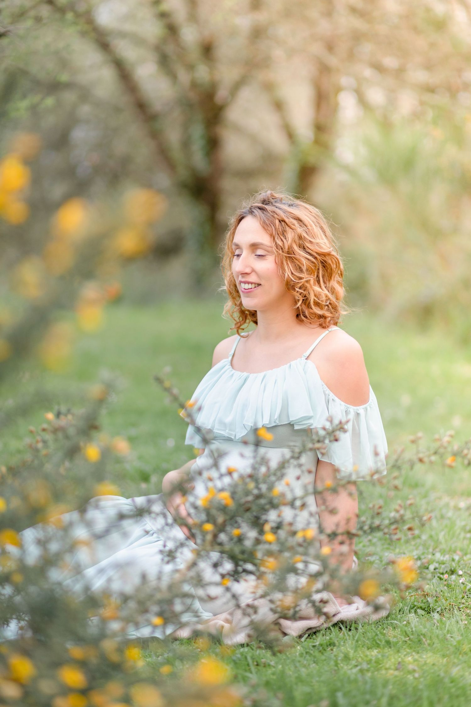 Artistic maternity portrait amidst blooming yellow wildflowers and natural greenery.