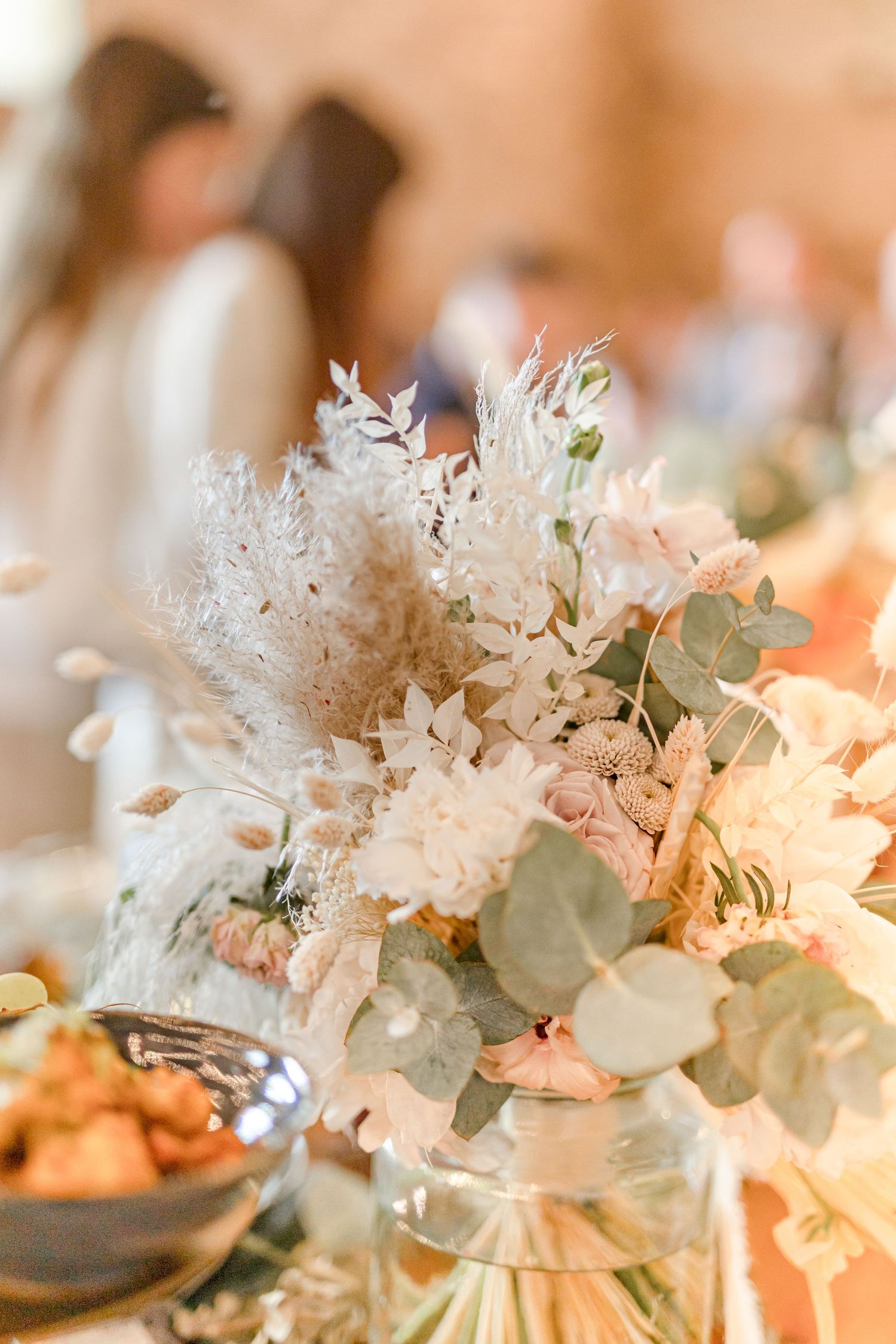 Elegant table centerpiece with white dried flowers, eucalyptus leaves and soft pink accents.