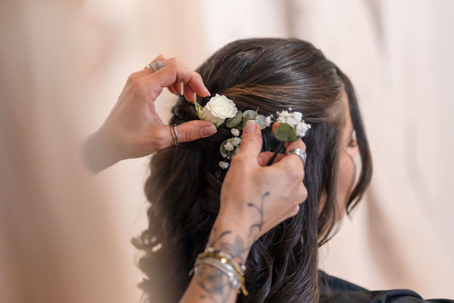 White flowers being carefully pinned into dark hair during styling.