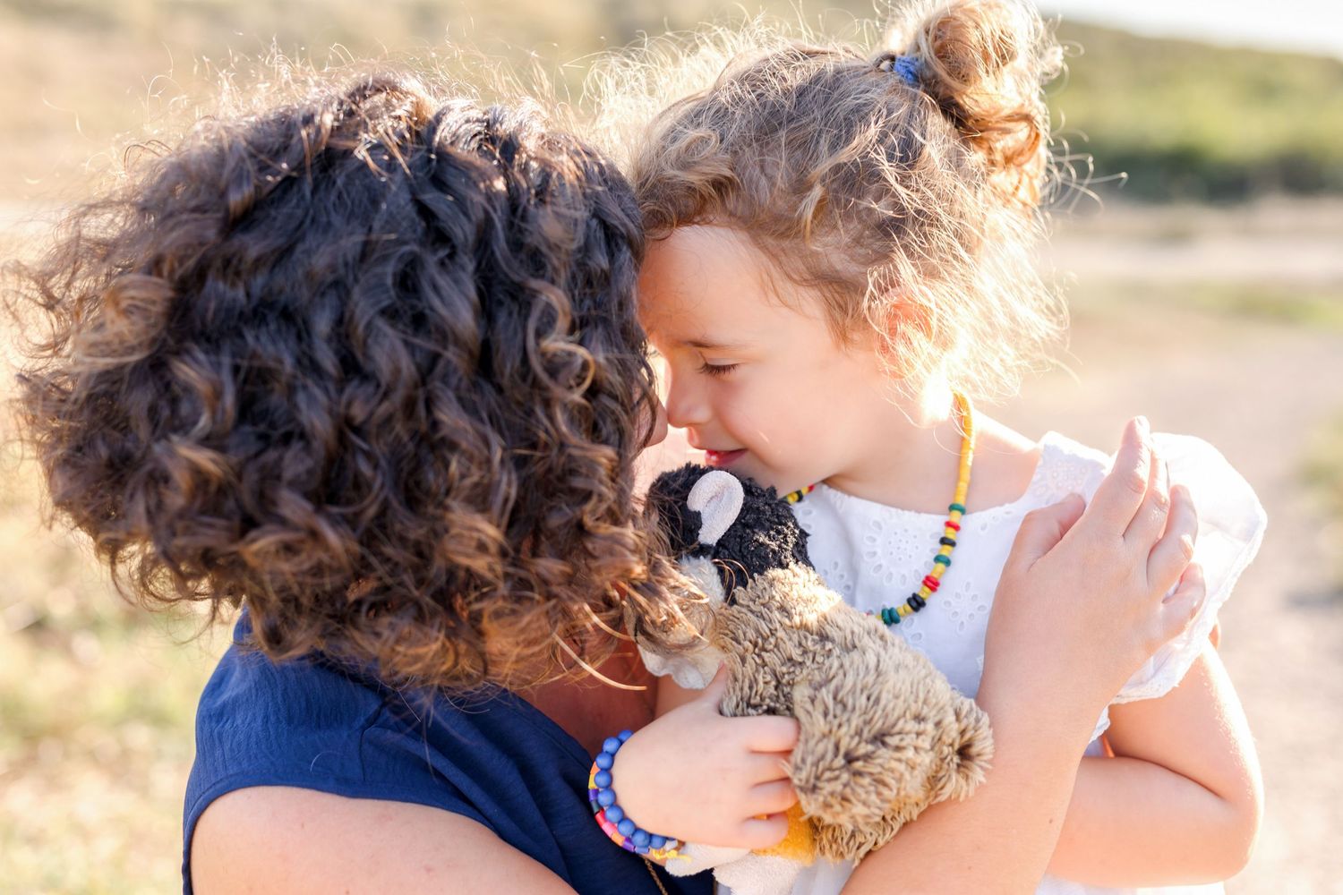 Loving embrace between parent and child with soft sunset lighting in nature.
