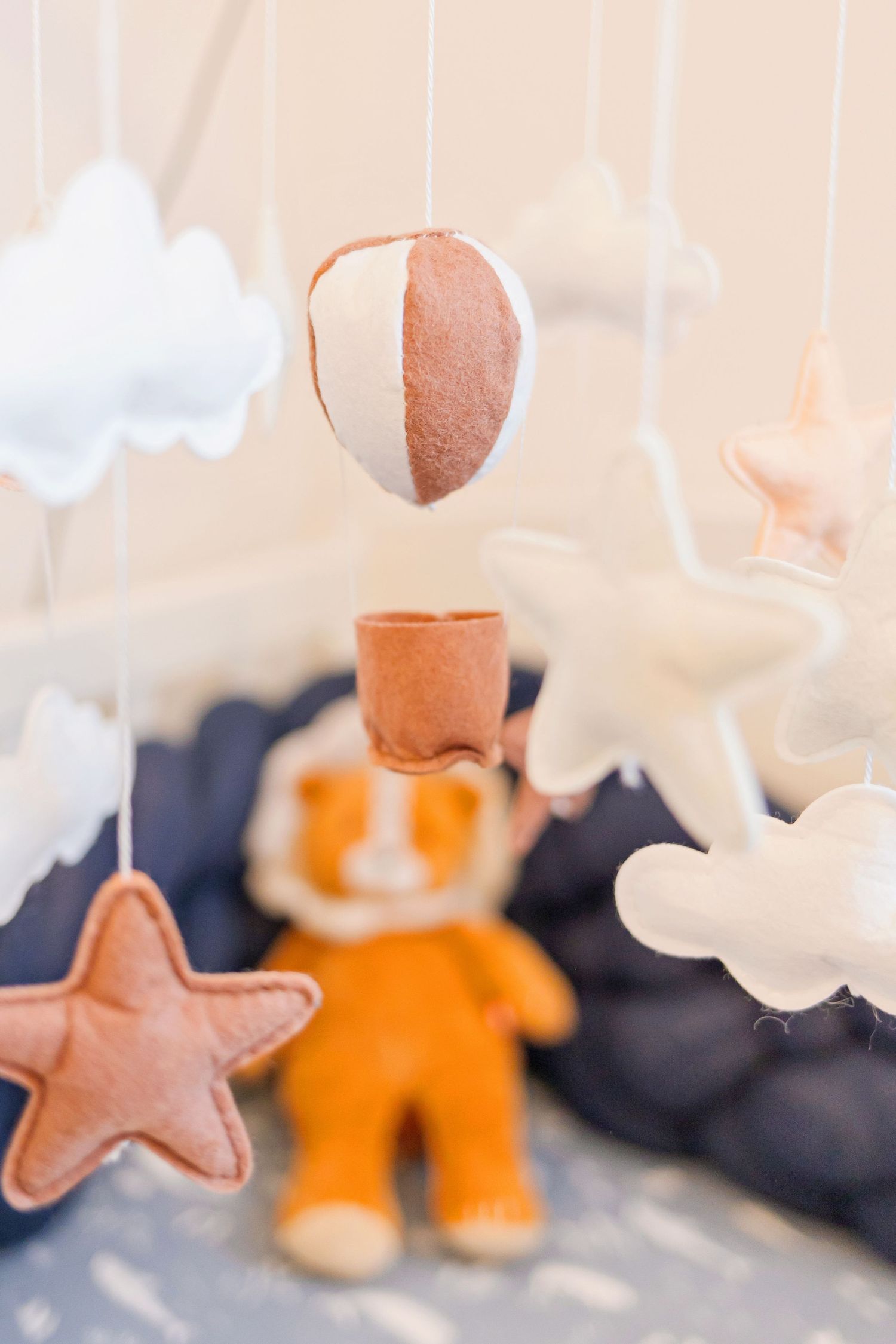 Nursery mobile with felt clouds, stars and hot air balloon in peach and navy colors.