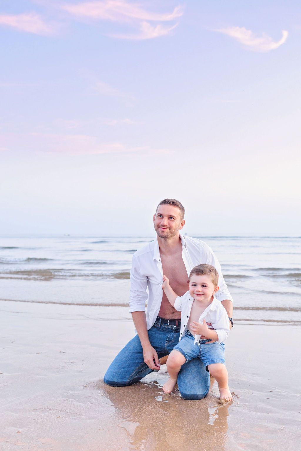 Father and young child share playful moment on beach at sunset.