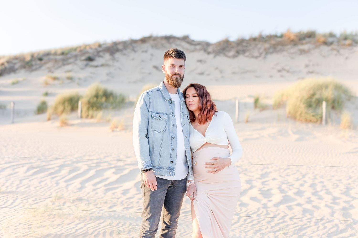 Couple enjoying a romantic moment on sandy dunes at sunset.