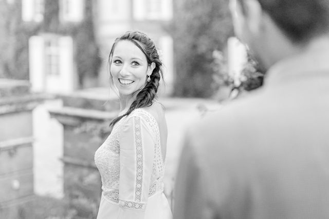 Black and white portrait of bride with braided hairstyle looking over shoulder.