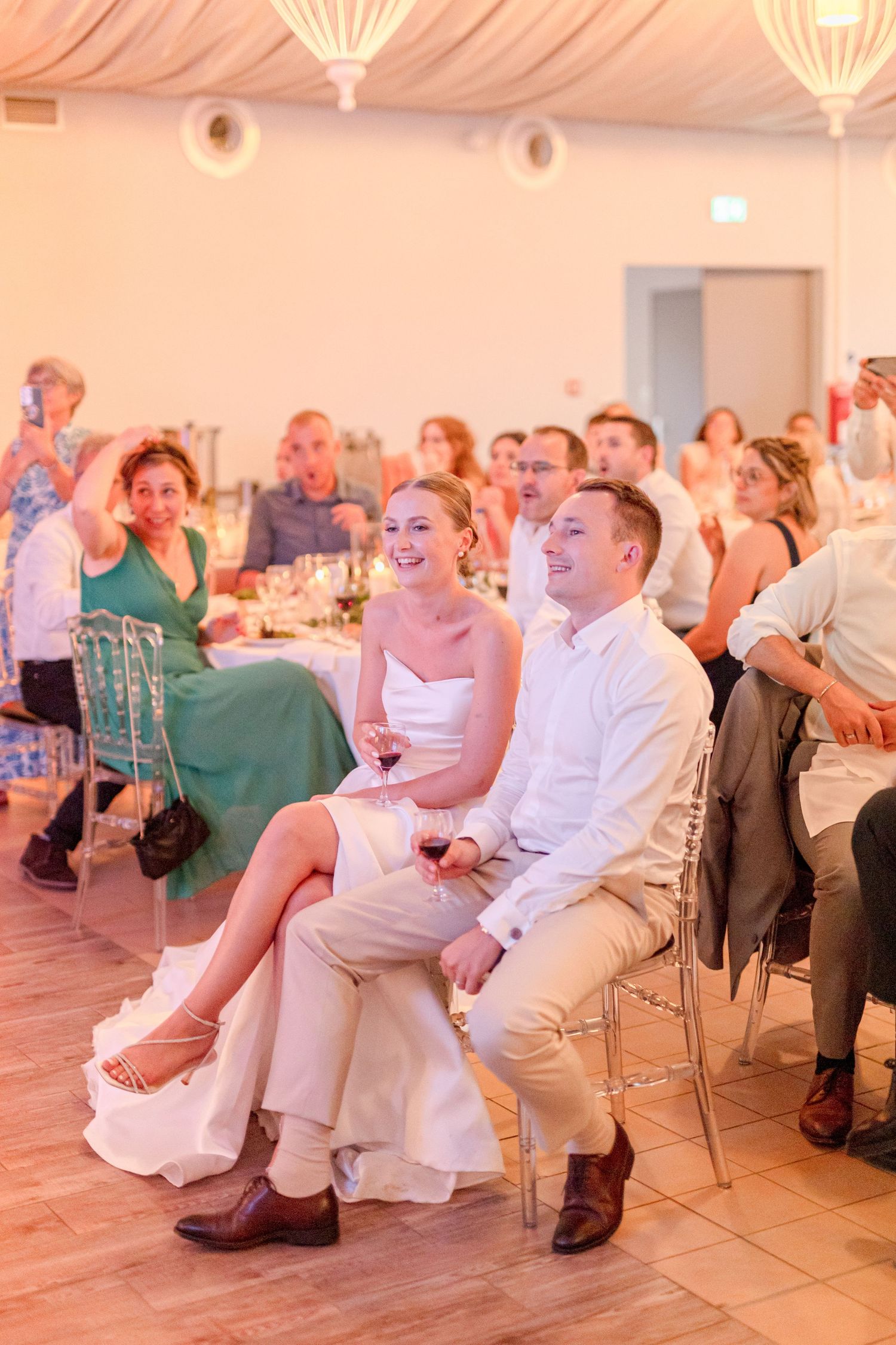 Wedding guests watching presentation in beautifully lit reception hall.