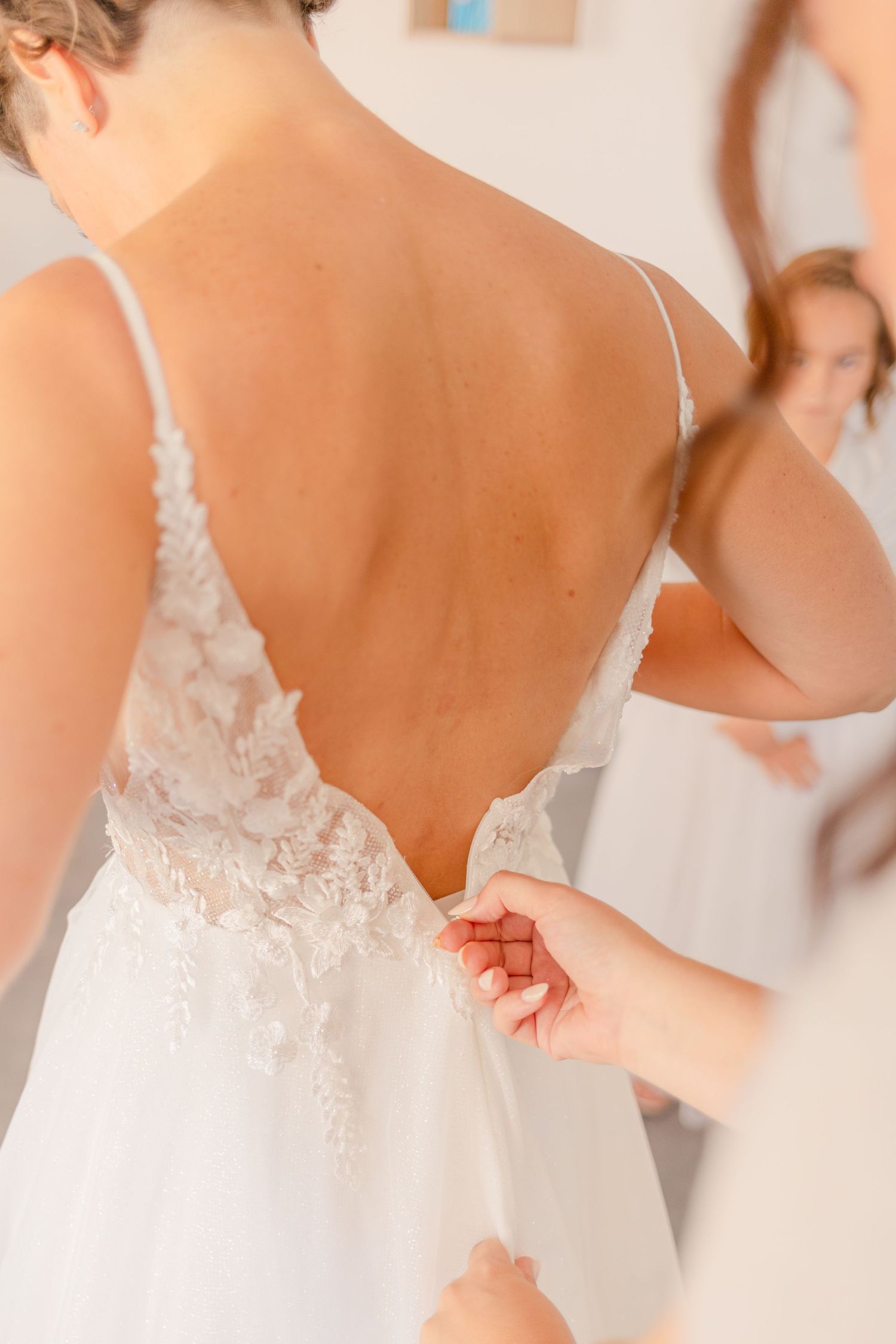 Detail shot of delicate lace wedding dress being fastened.