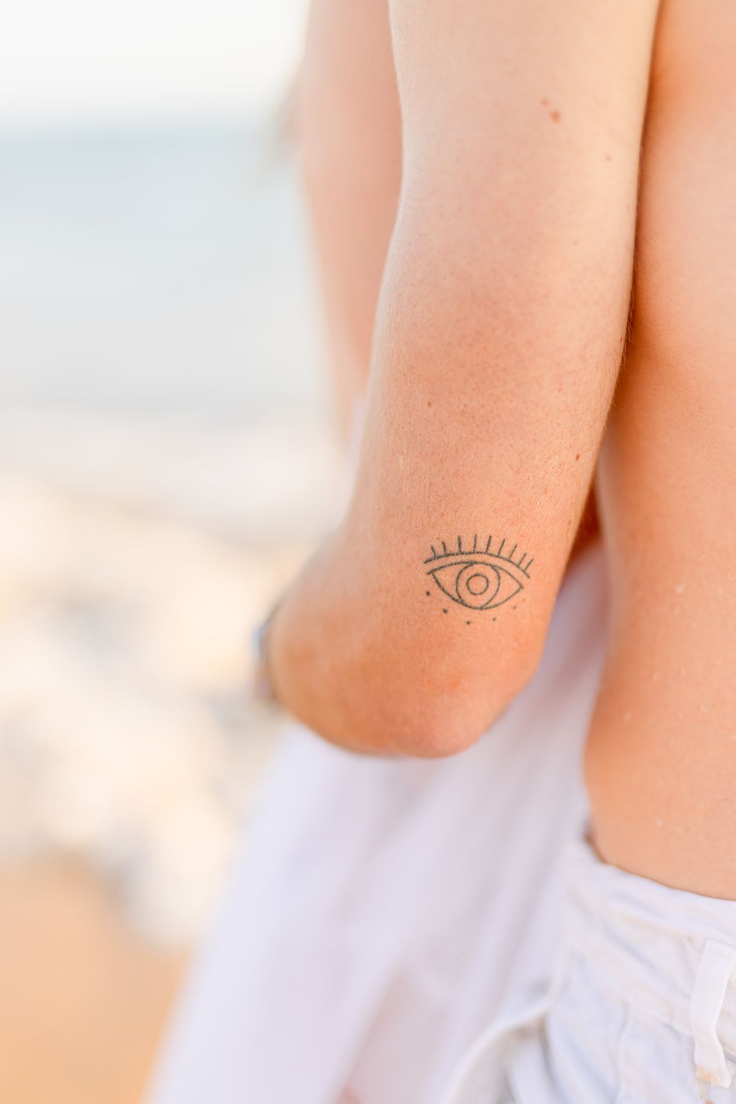 Small decorative minimalist eye tattoo design inked on a person's arm or wrist area.