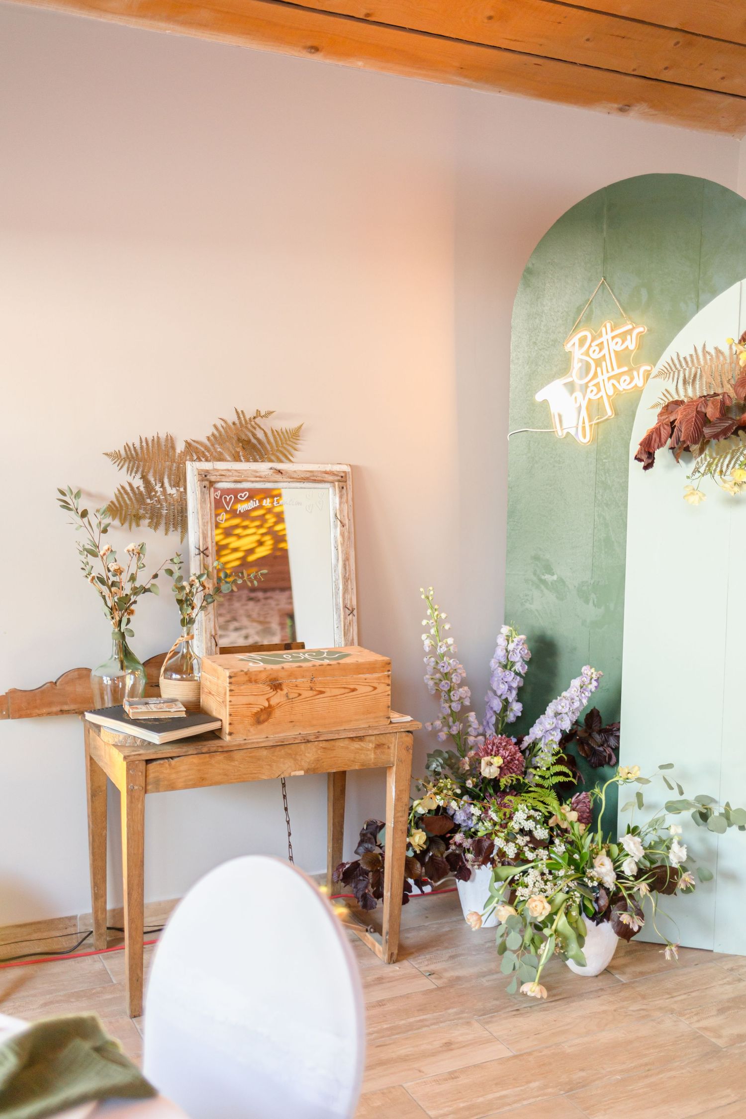 Wedding reception venue with rustic wooden furniture and floral arrangements against mint green walls.