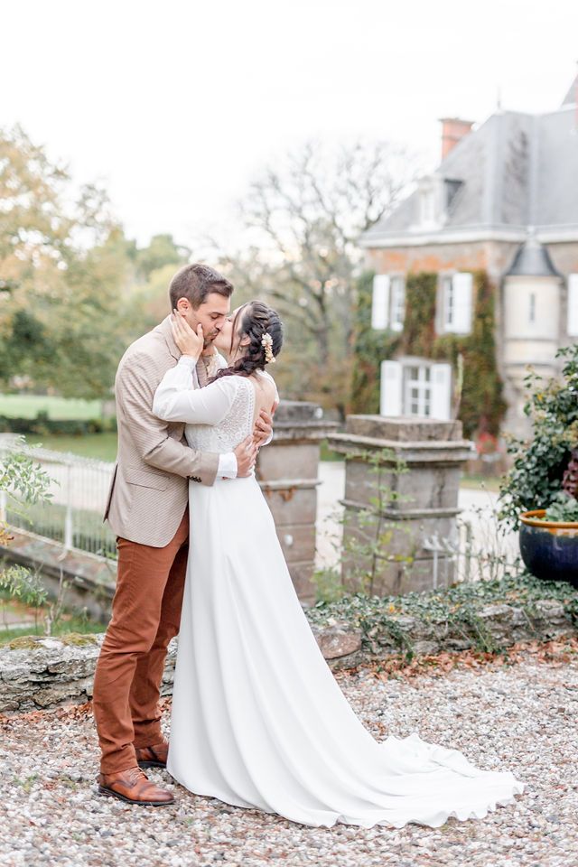 Elegant wedding couple sharing intimate moment in front of historic French estate.