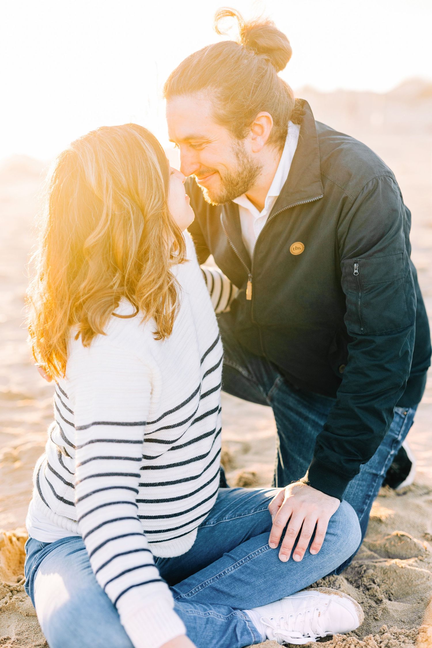 Romantic couple embracing on beach sand during golden hour sunset.