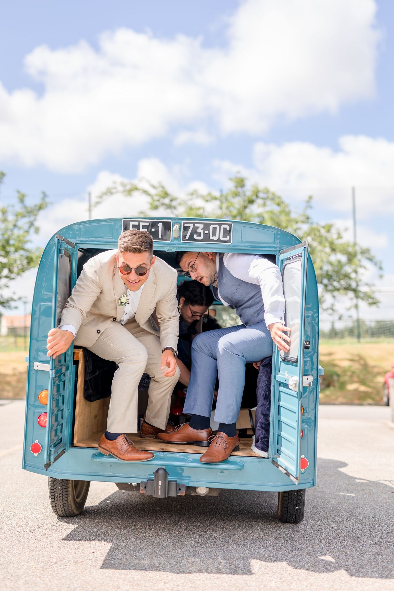 Two people laugh while sitting in back of classic blue Citroen delivery van.