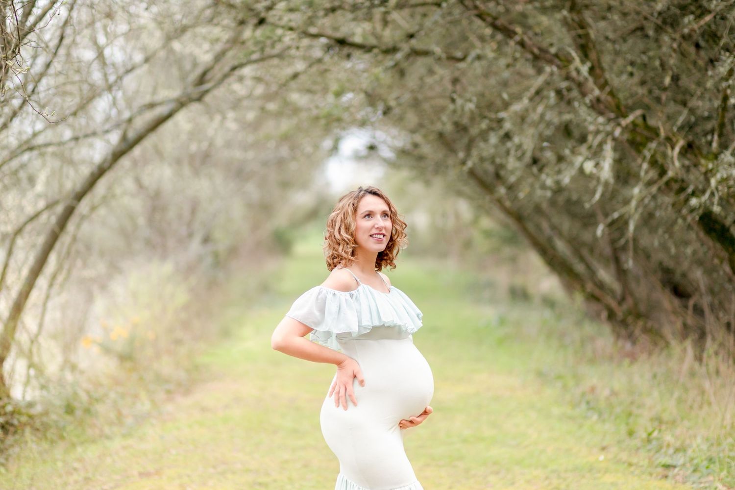A whimsical maternity portrait taken beneath a canopy of spring branches.