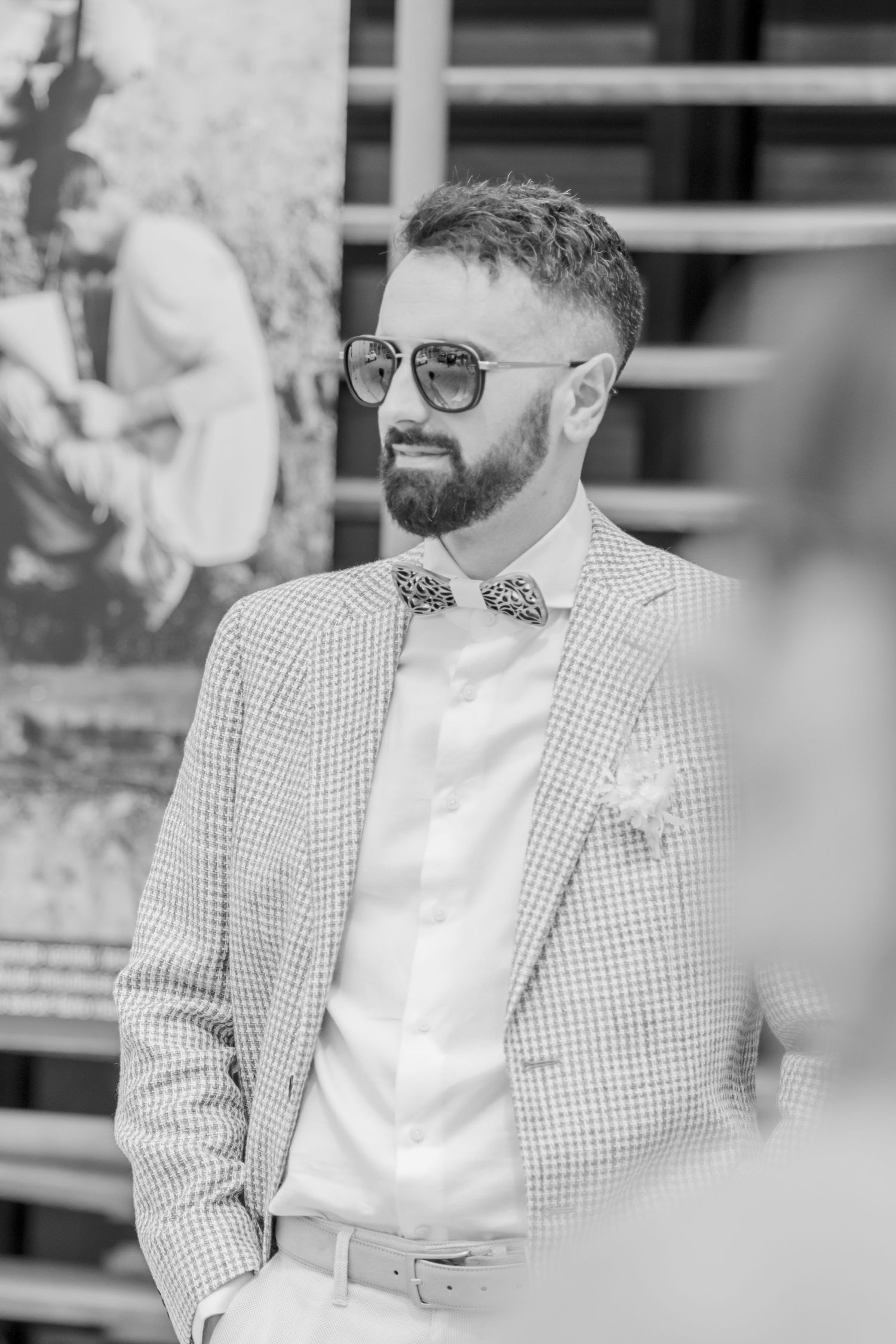 Close-up of guest in checkered suit jacket and bow tie at formal event.
