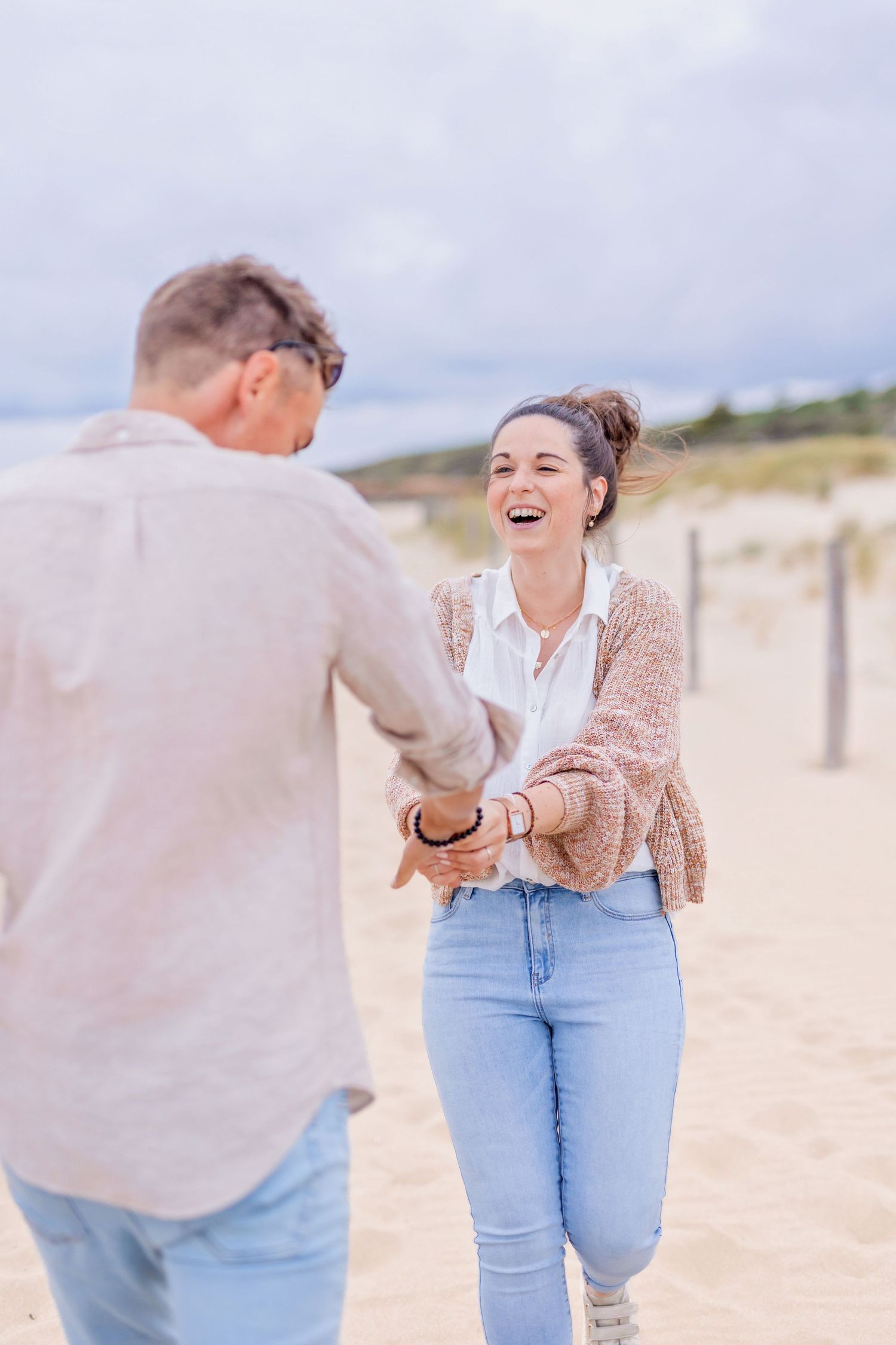 Candid beach photoshoot showing laughter and joy between two people on sandy shores.