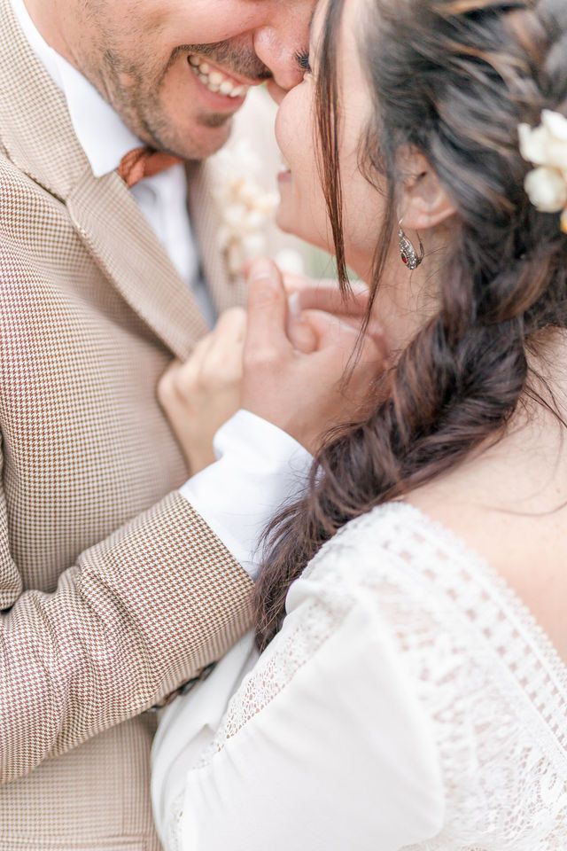Intimate close-up of newlyweds sharing a tender moment in beige and white wedding attire.