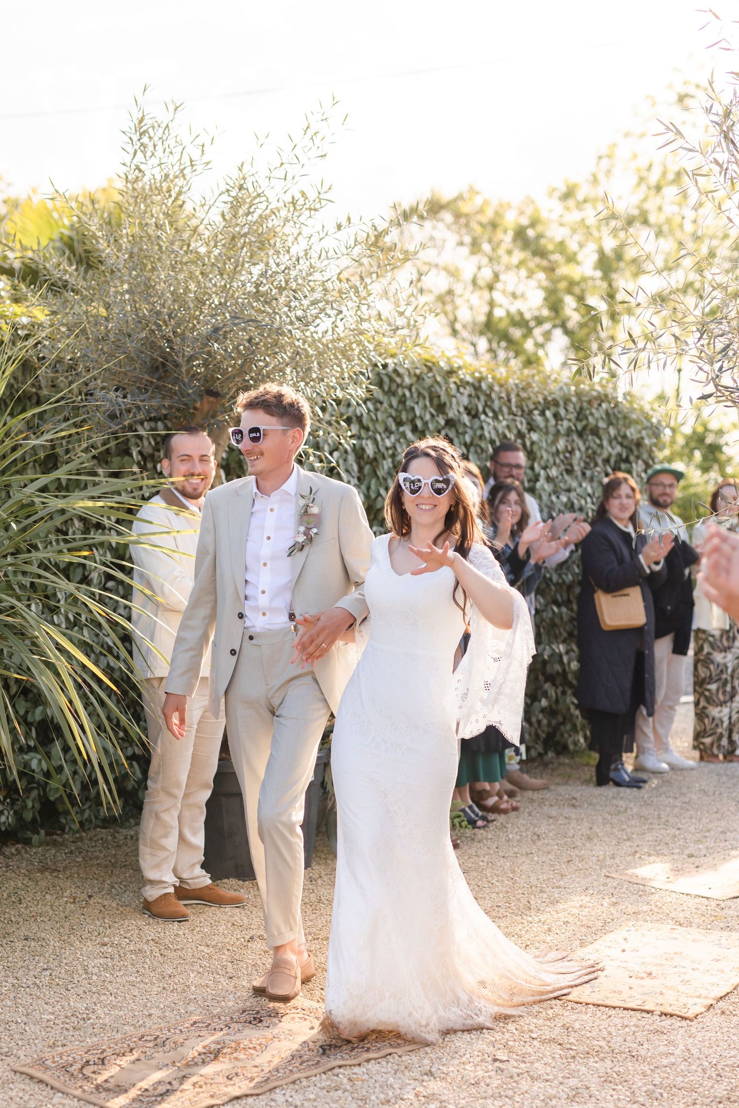 Wedding celebration outdoors with guests clapping and cheering at a garden venue.