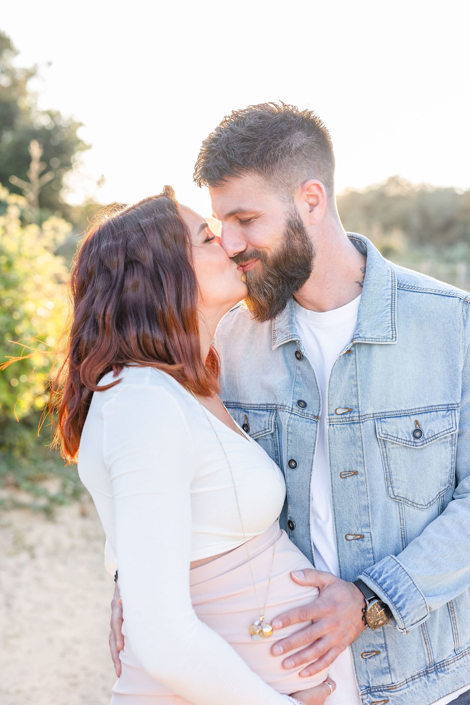 Intimate maternity moment captured between couple in natural outdoor setting.