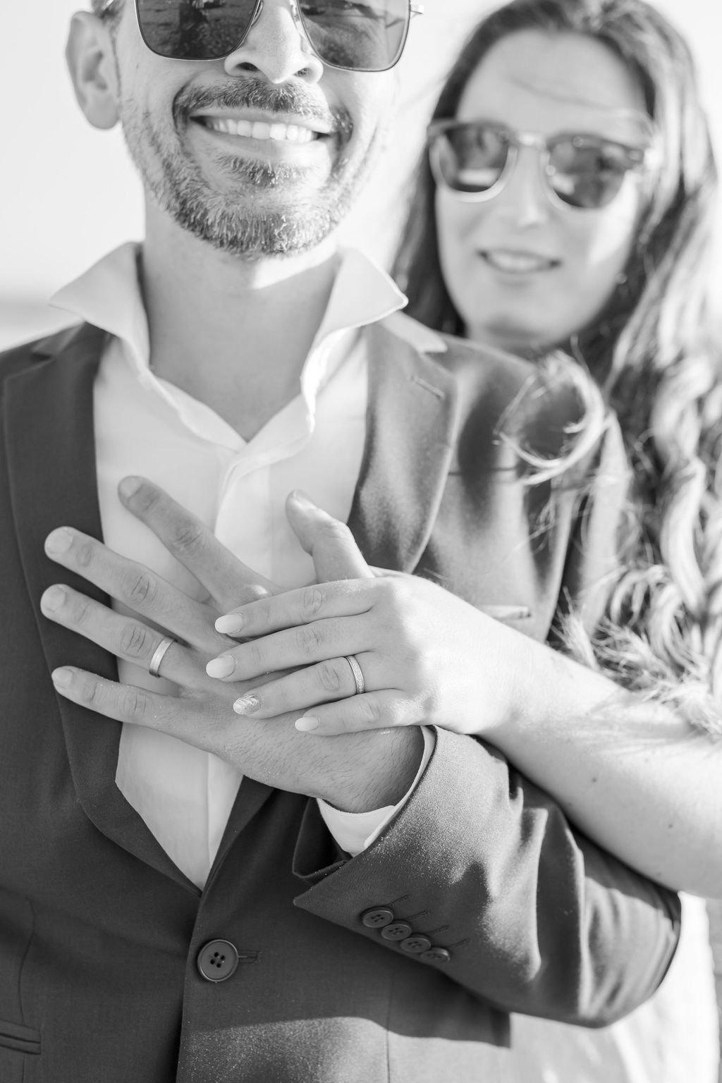 Close up of hands showing wedding rings during beach celebration.