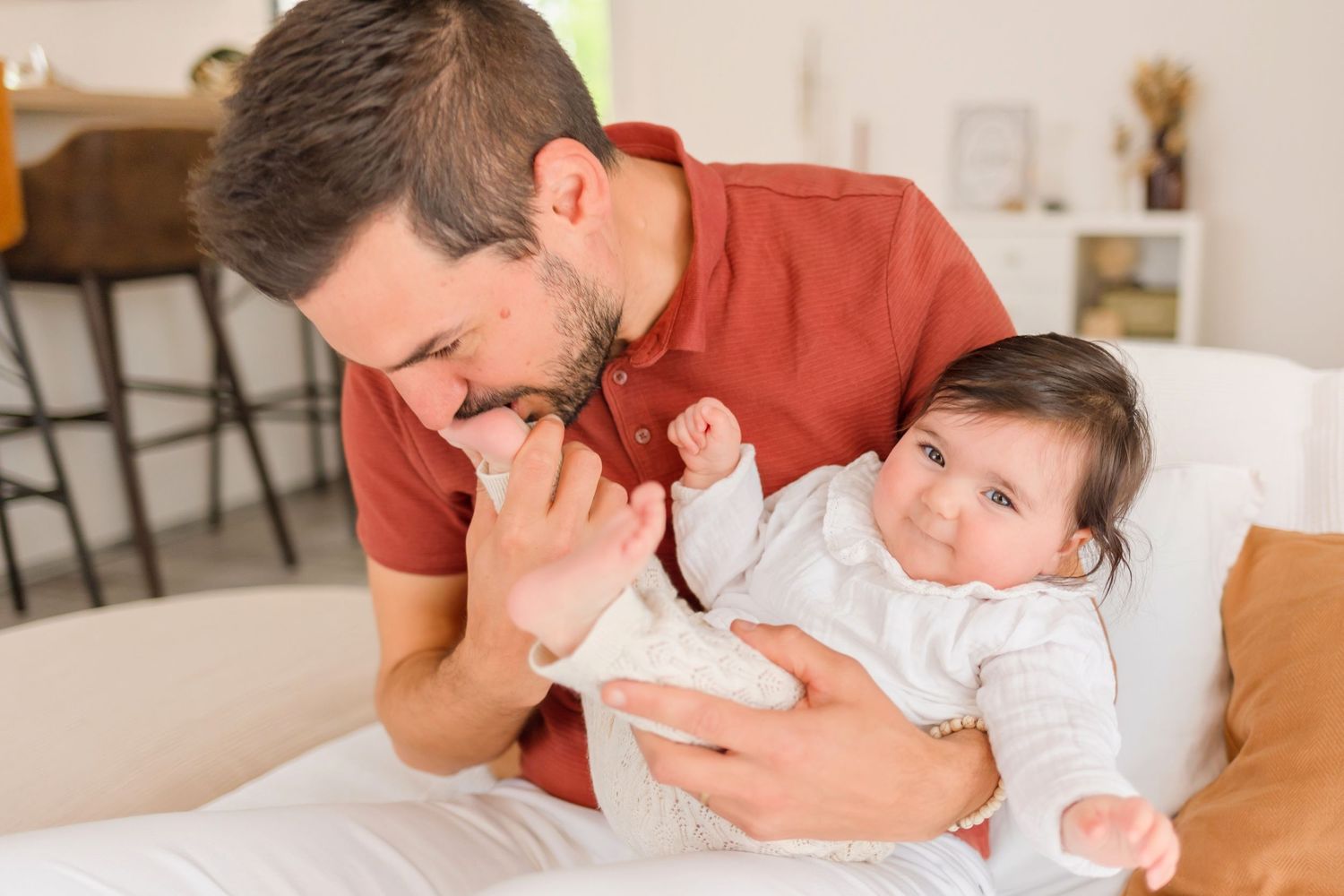 A tender family moment as they snuggle with a newborn baby in a light-filled room.