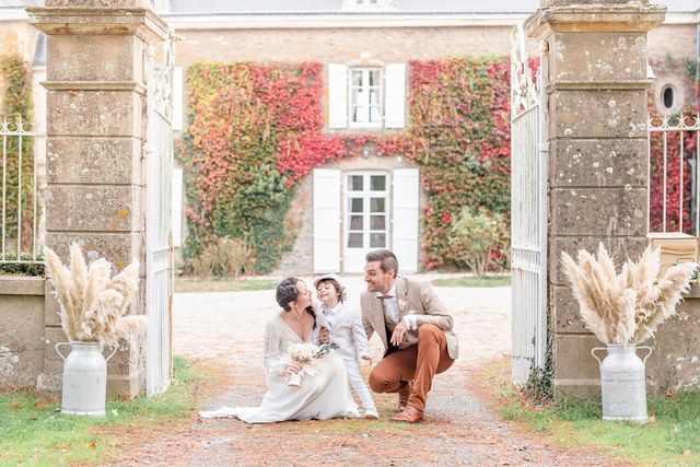 Bright family portrait between stone gates with pampas grass arrangements at chateau entrance.