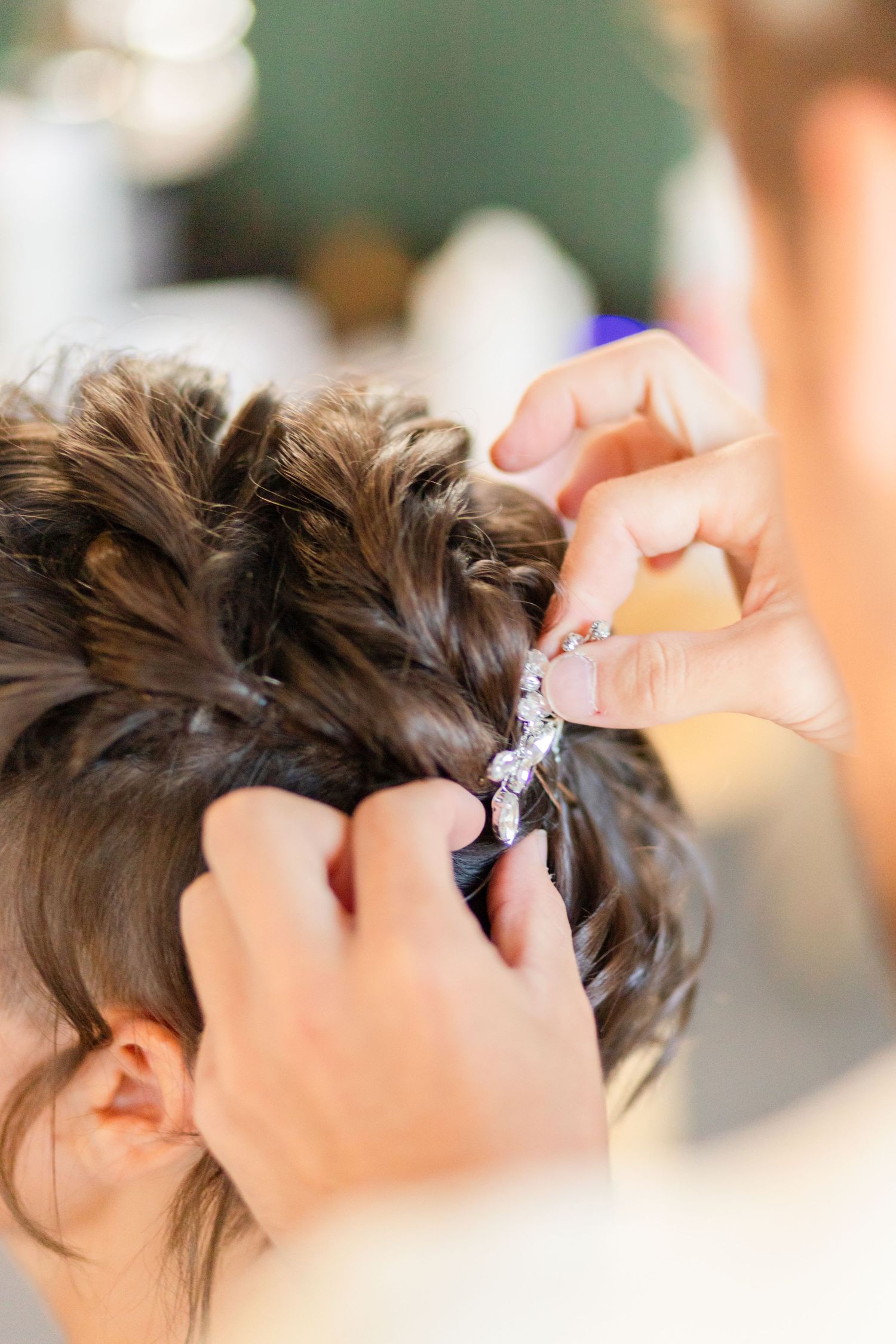 Close-up of hands styling and pinning hair for wedding preparation.