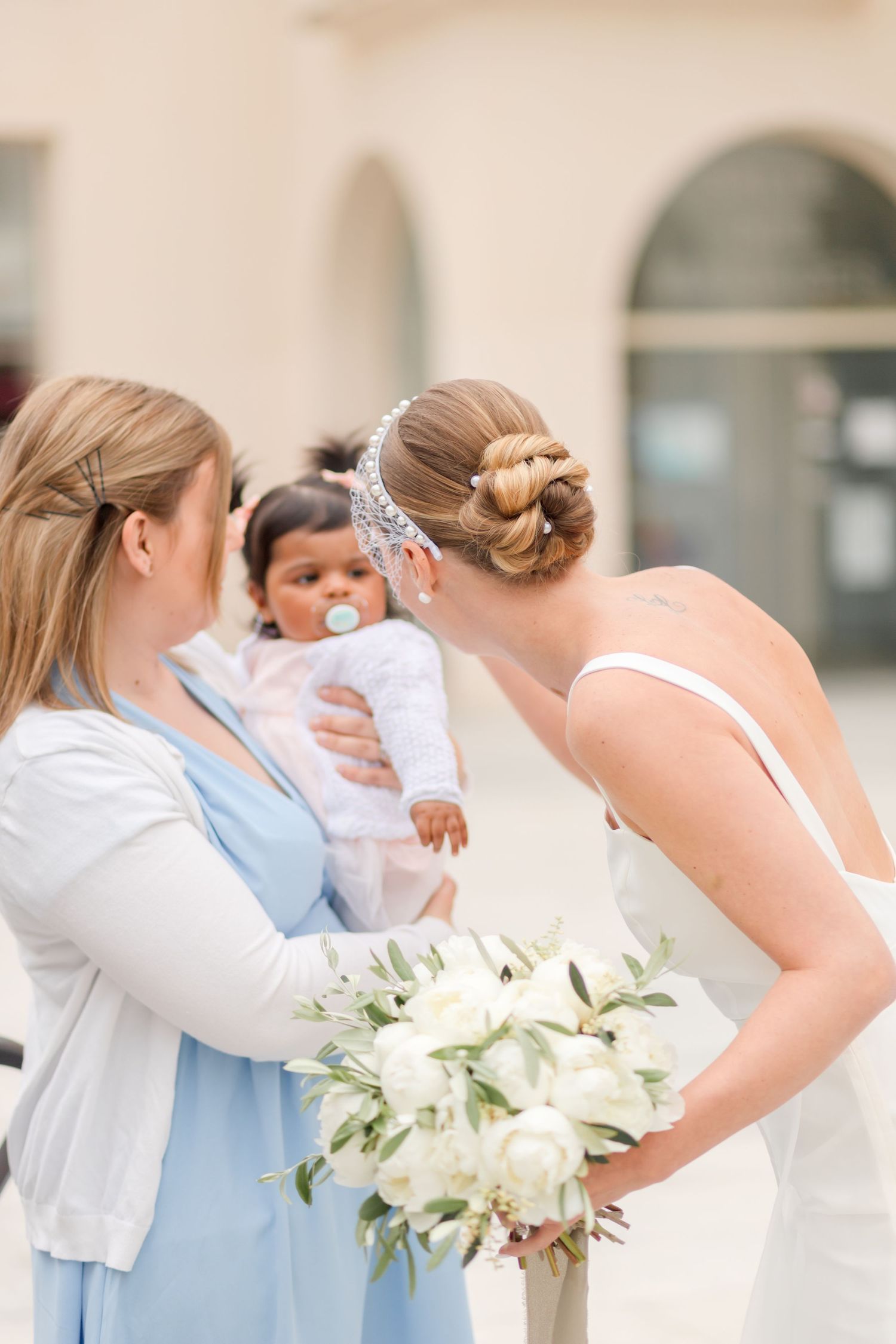 Bridesmaids in light blue dresses holding white floral bouquets during outdoor ceremony.
