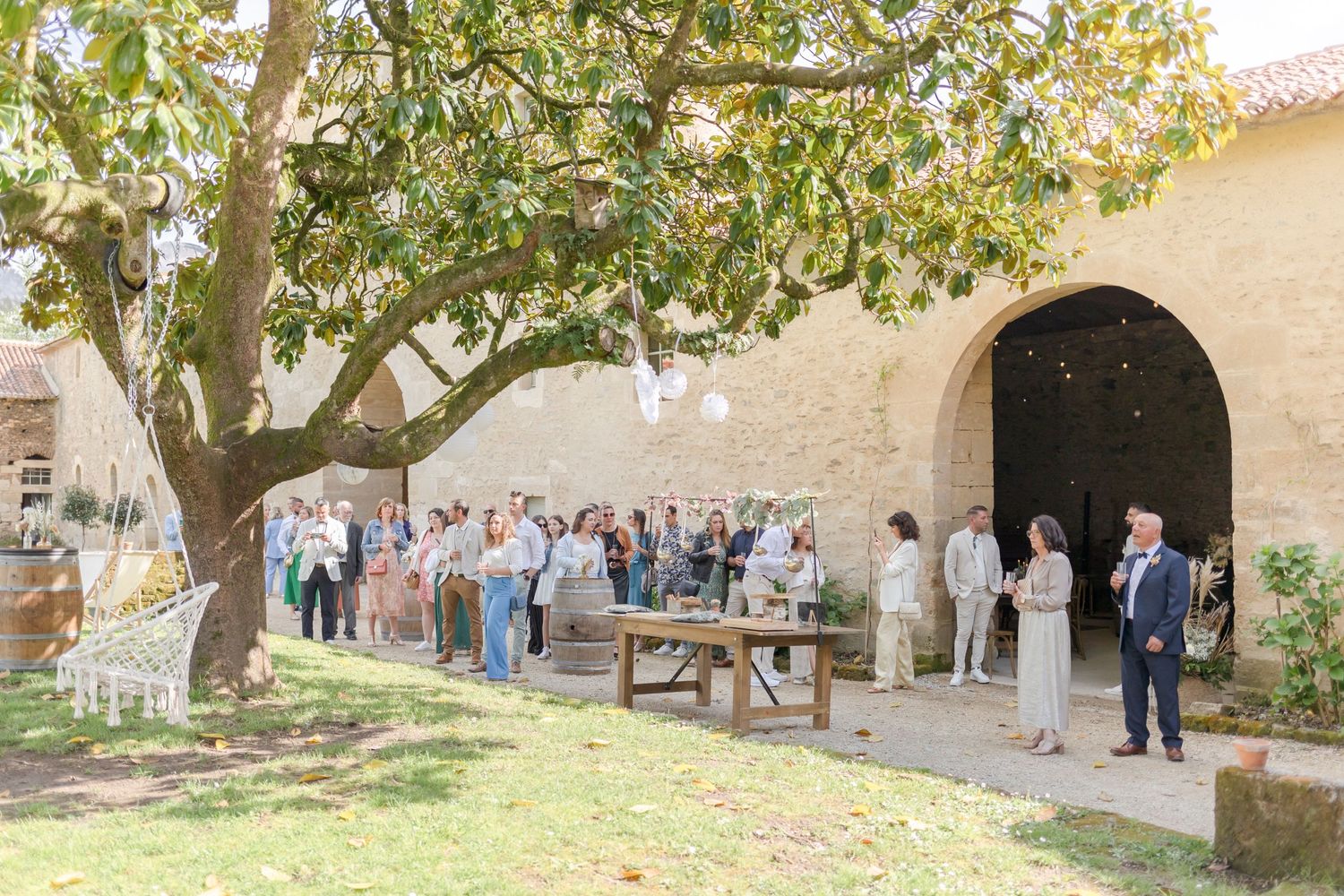 Outdoor gathering in a Mediterranean-style courtyard under large shade trees.