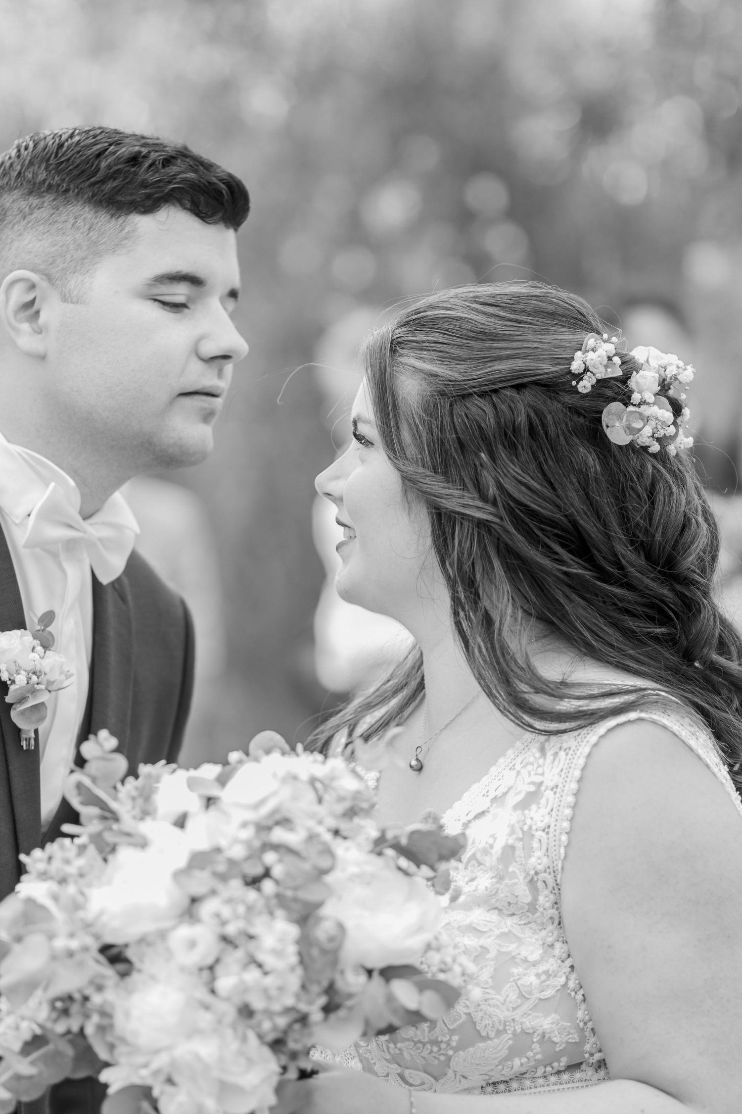Intimate black and white portrait of couple sharing tender moment with floral bouquet.