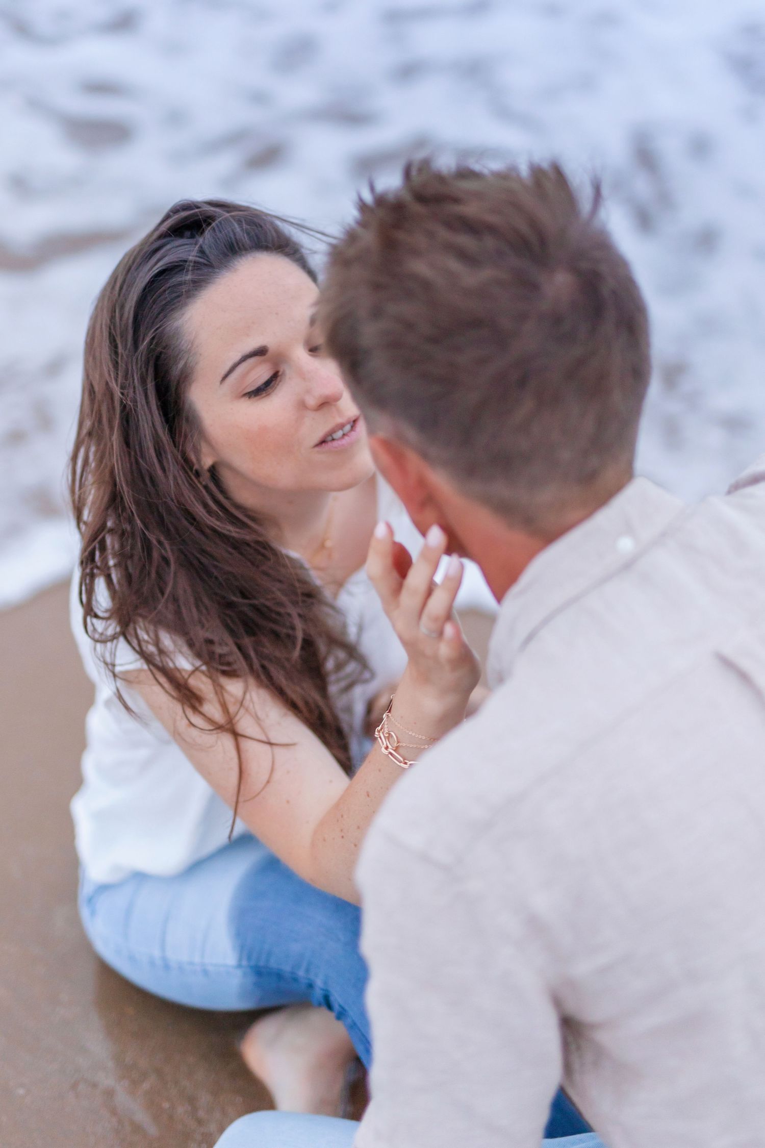 A tender moment shared between two people sitting on a sandy beach.