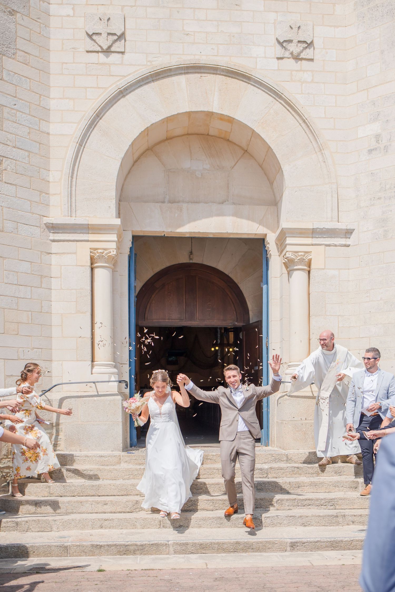 Wedding party poses on church steps in joyful celebration.