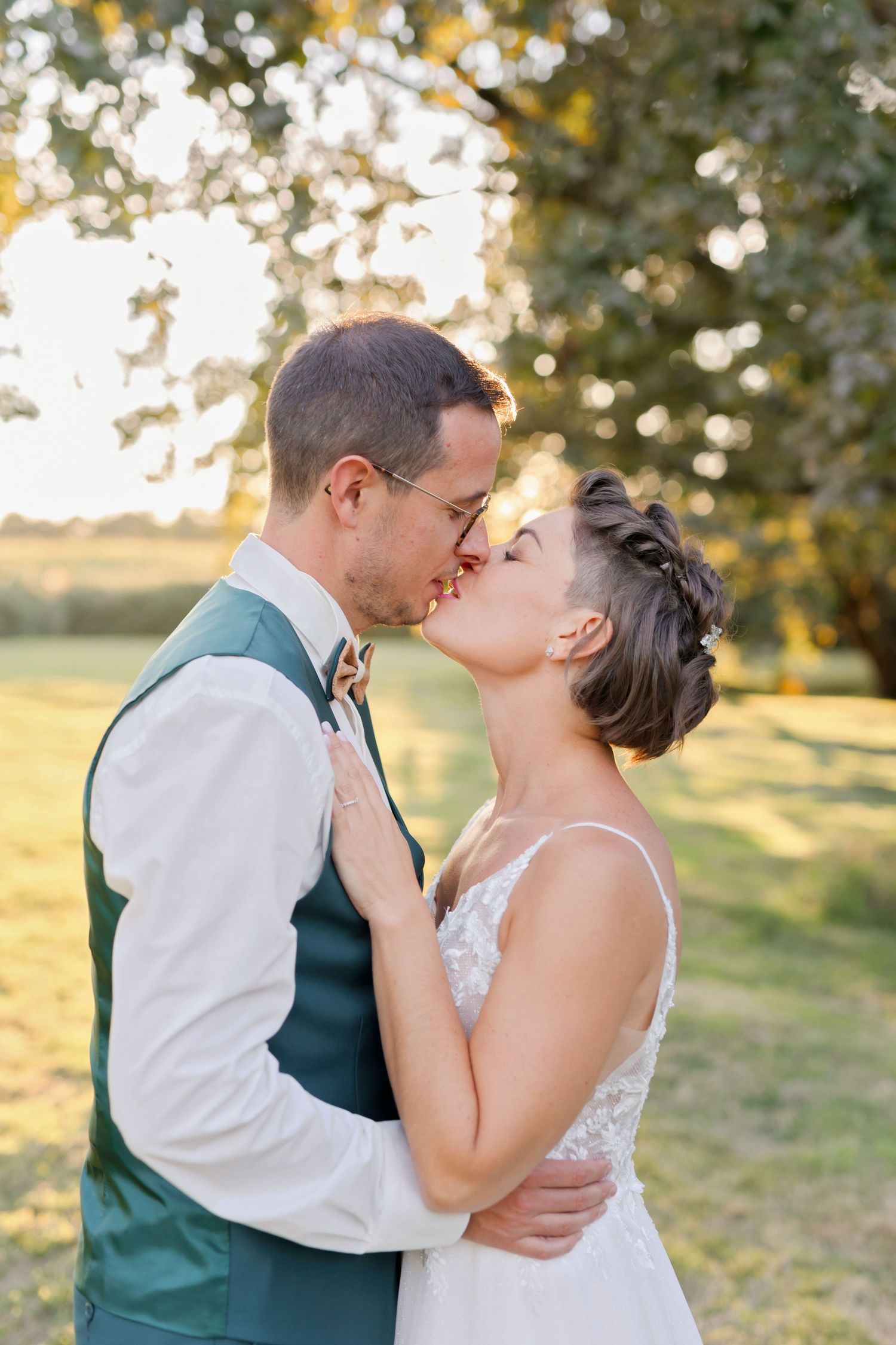 Golden hour wedding portraits in a grassy field with soft natural lighting.