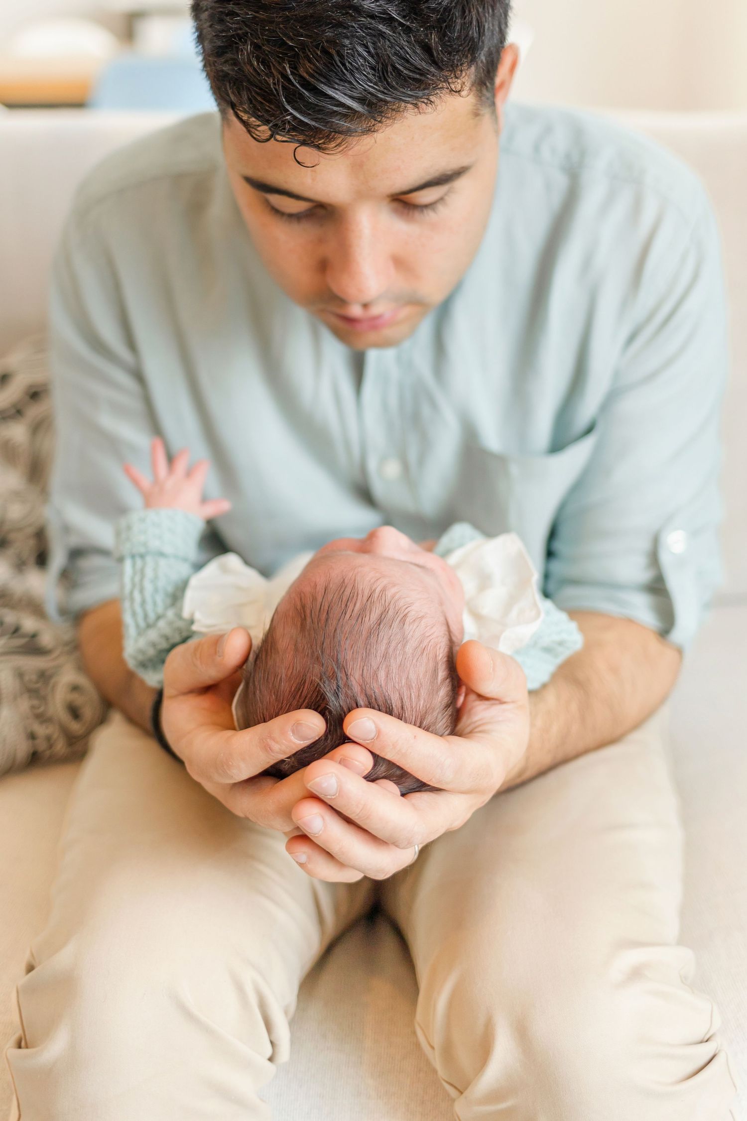 Close-up of caring parent gently holding newborn baby in cupped hands.