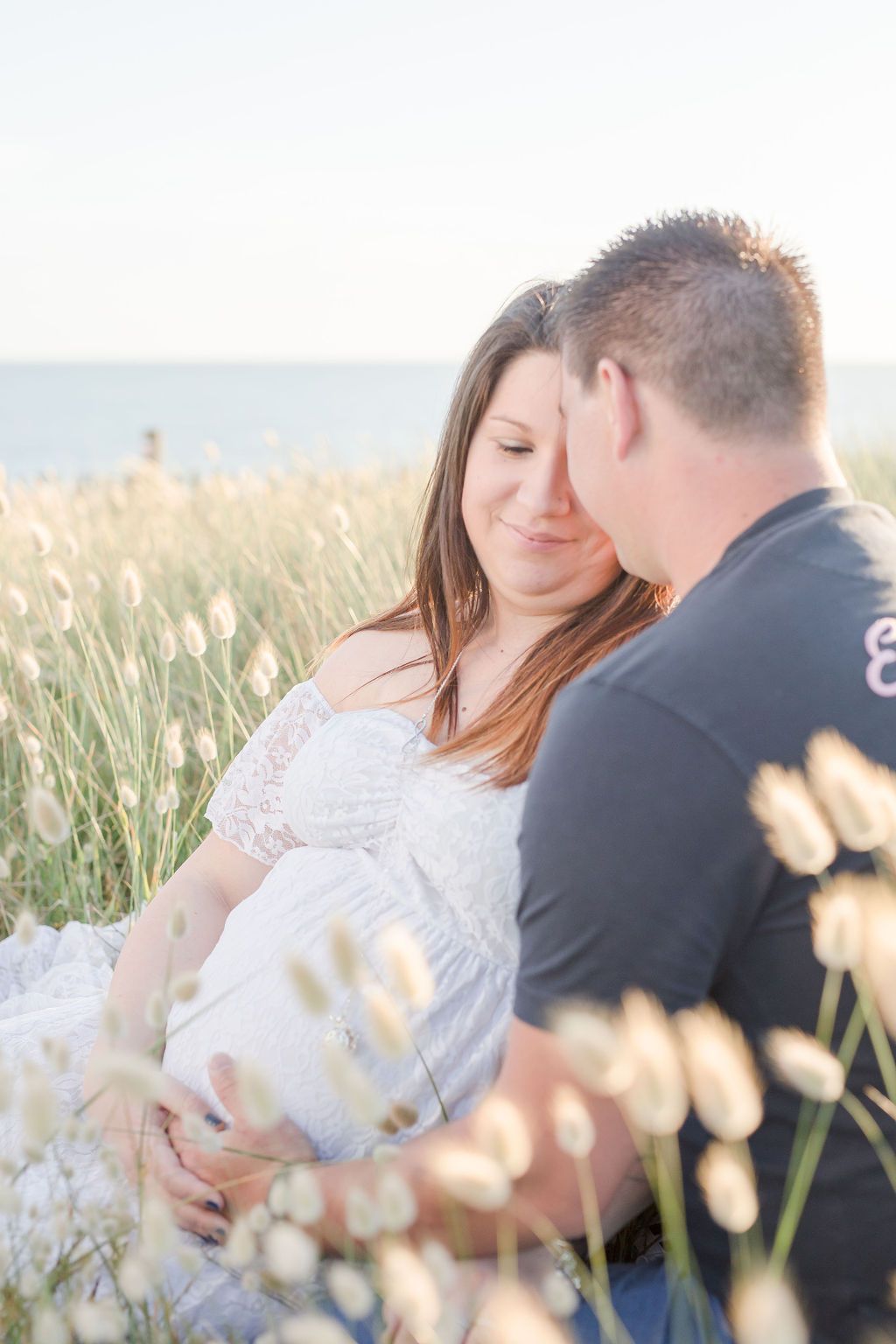 A romantic photoshoot in a meadow with white flowers and soft natural lighting.