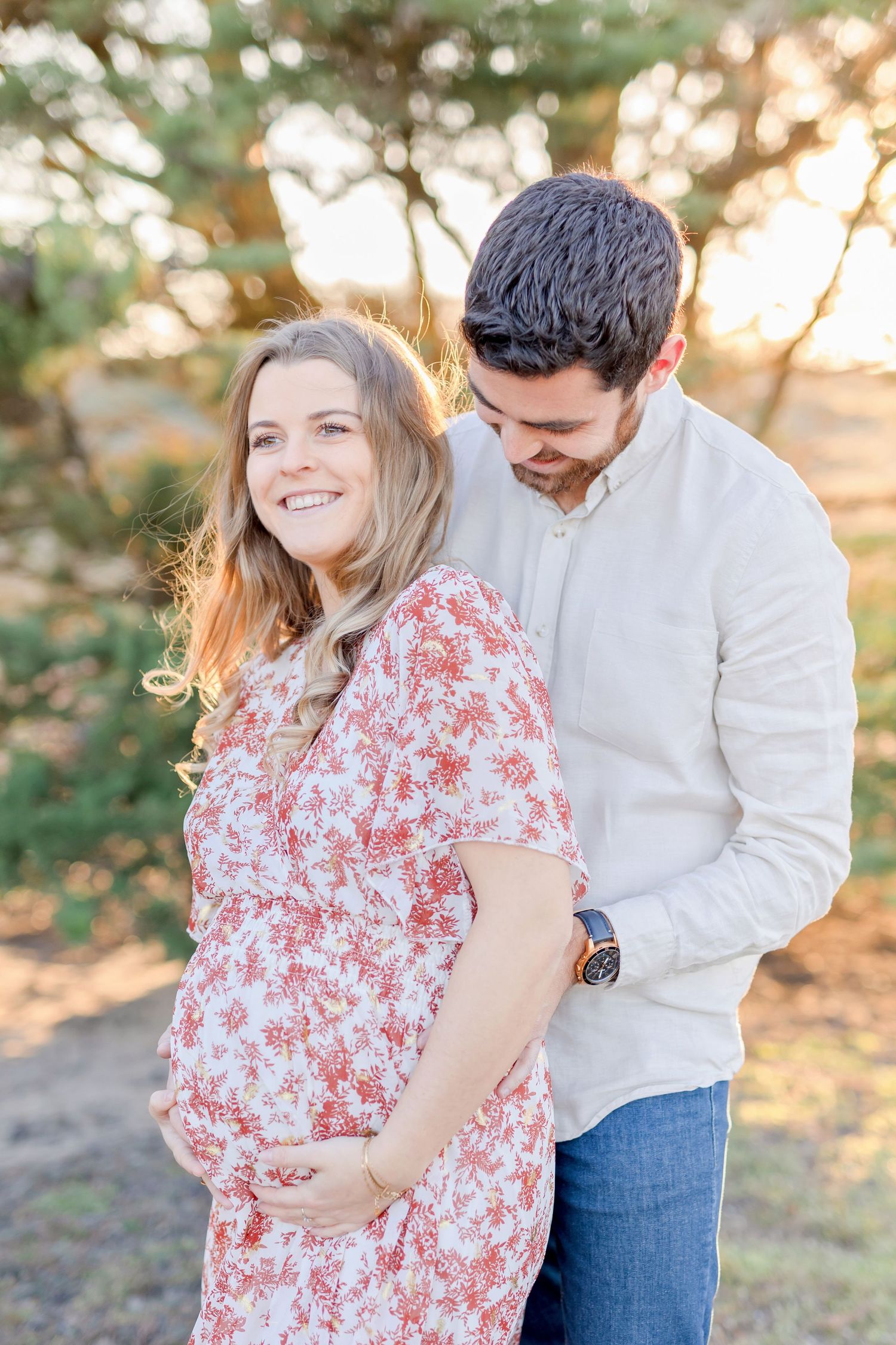 Happy couple shares candid moment during outdoor maternity photoshoot.