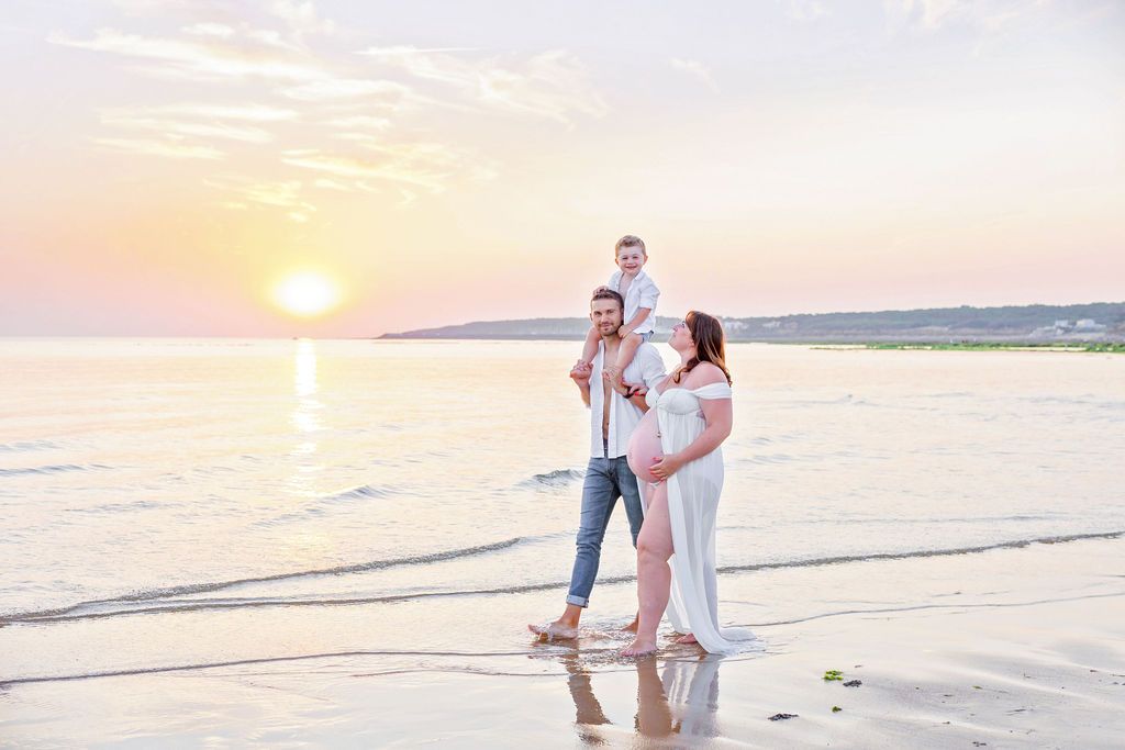 Family enjoying a sunset moment together on beach with orange sky.