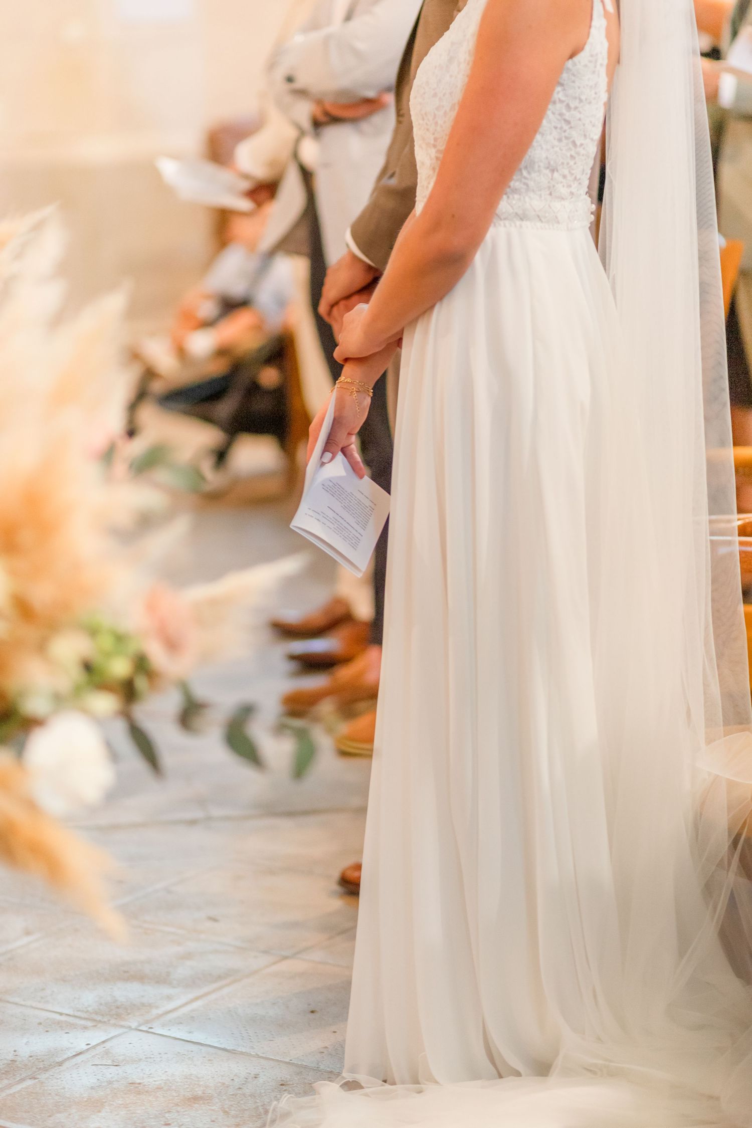 Wedding dress details and ring exchange in soft church lighting.