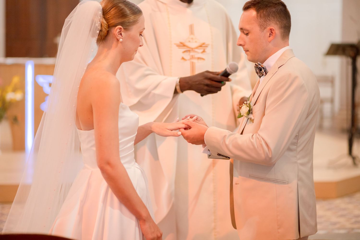 A tender moment during a ring exchange ceremony in a church with soft lighting.