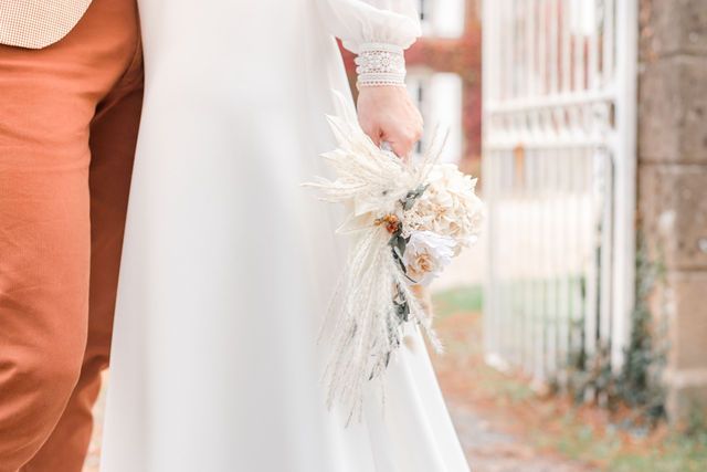 Delicate details of a bride's lace dress and dried flower bouquet against soft neutral backgrounds.