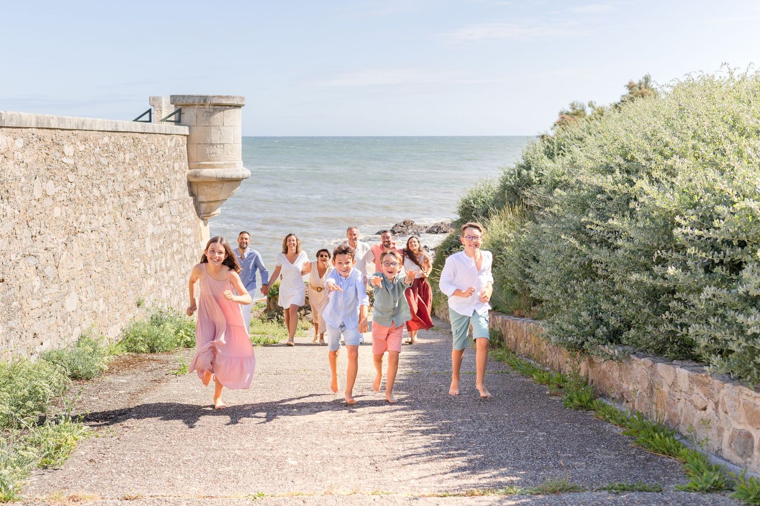 A group wearing coordinated white outfits walks along a scenic beach path during sunset.