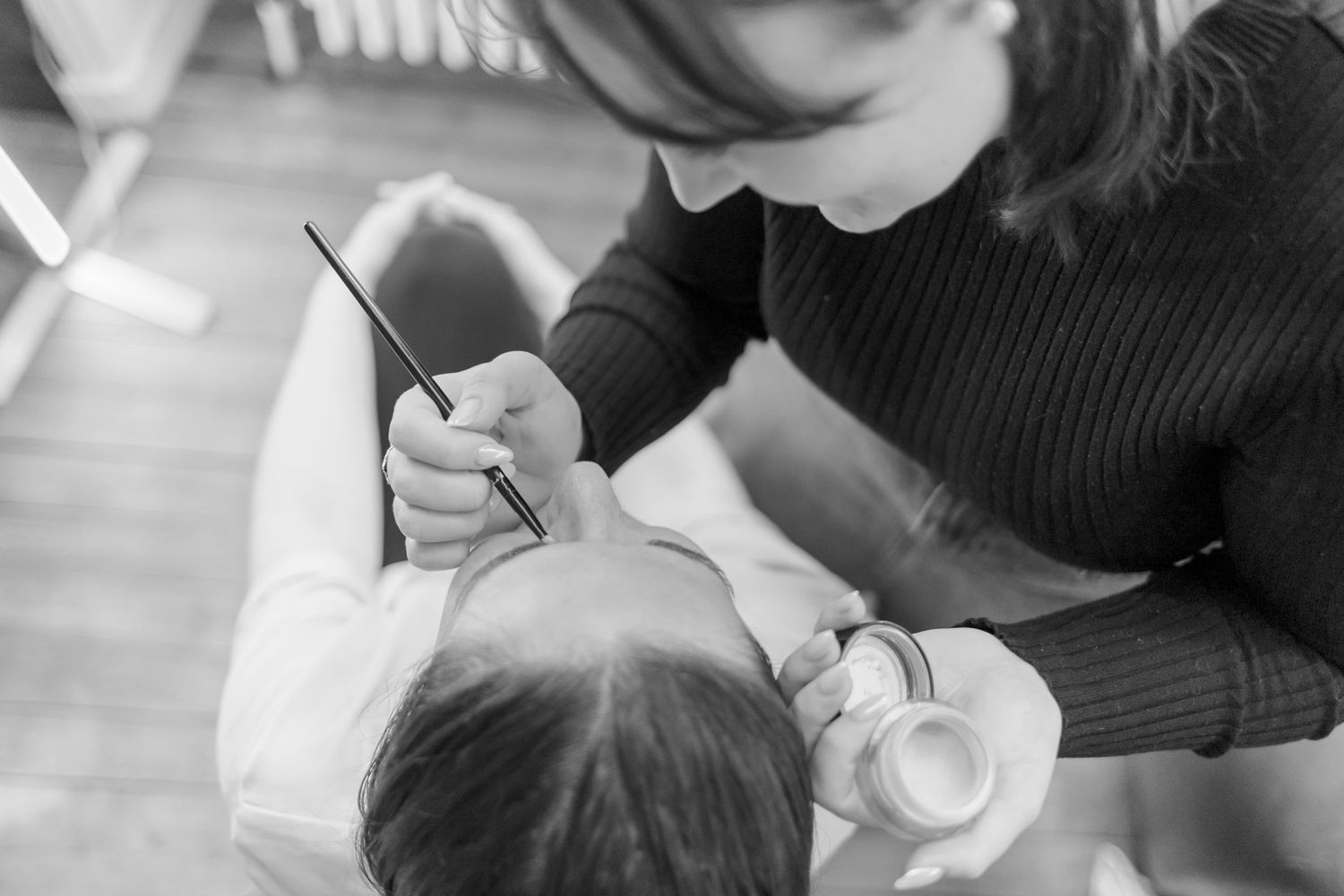 Close-up black and white image of someone feeding a baby with a bottle.