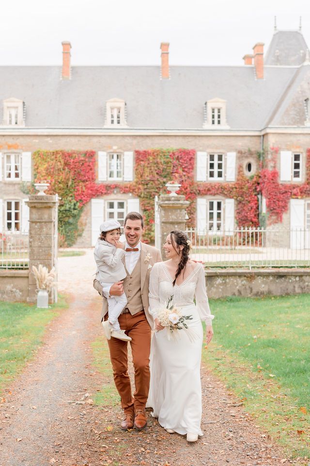 Wedding celebration on an autumn path leading to a historic French chateau.
