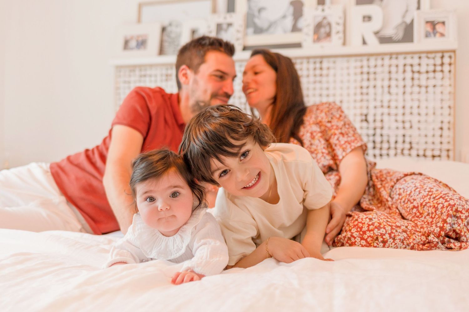 Happy family spending quality time together on a cozy white bed with warm lighting.