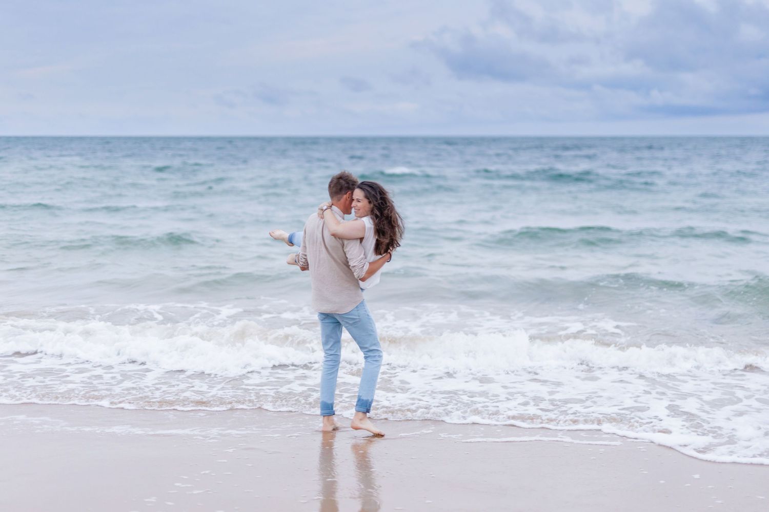 A playful moment captured on a sandy beach with ocean waves.