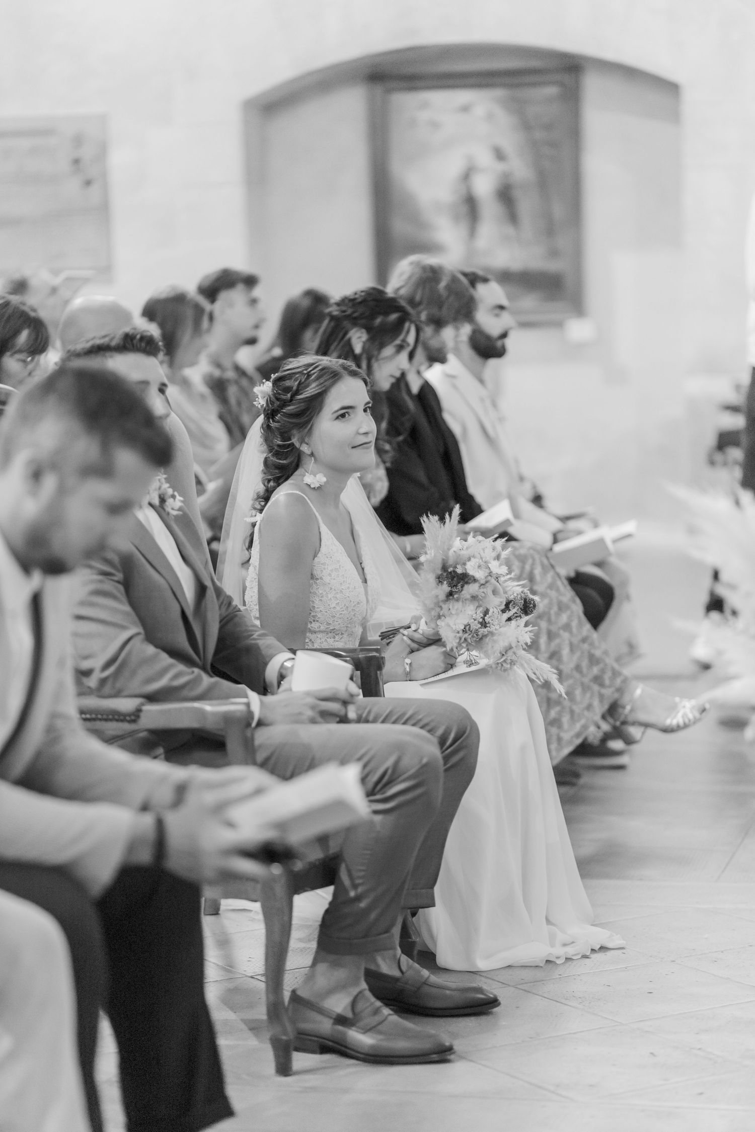 Wedding guests sit in church pews during an intimate ceremony.