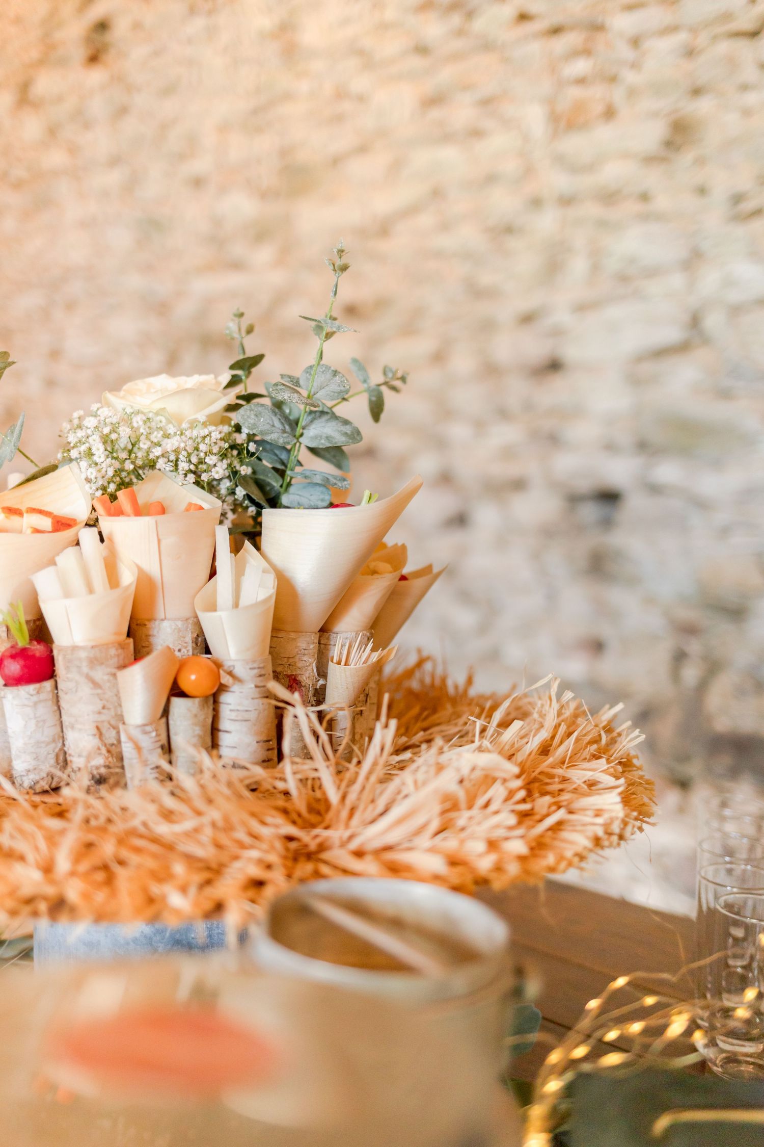 Decorative floral arrangements in paper cones displayed on natural straw setting.