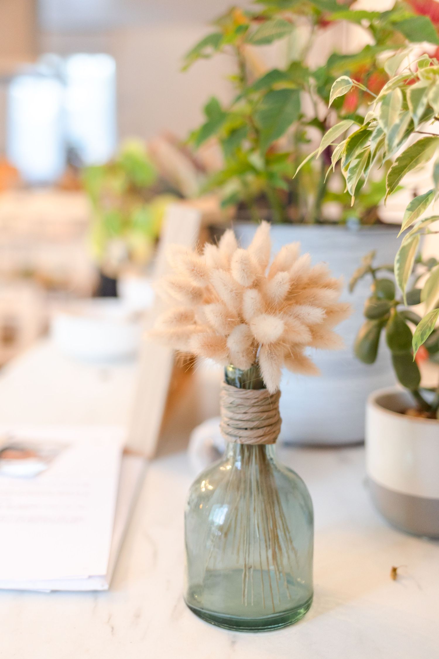 Delicate floral arrangements in glass vases decorate wedding reception tables.