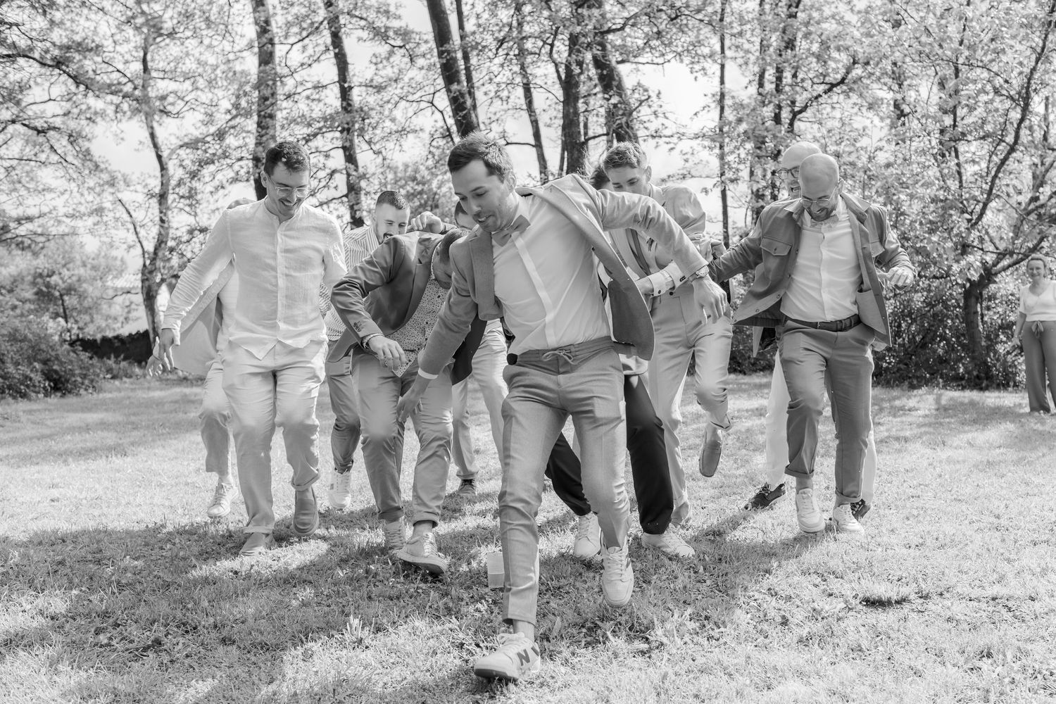 Black and white photo of celebratory group jumping and laughing together outdoors.
