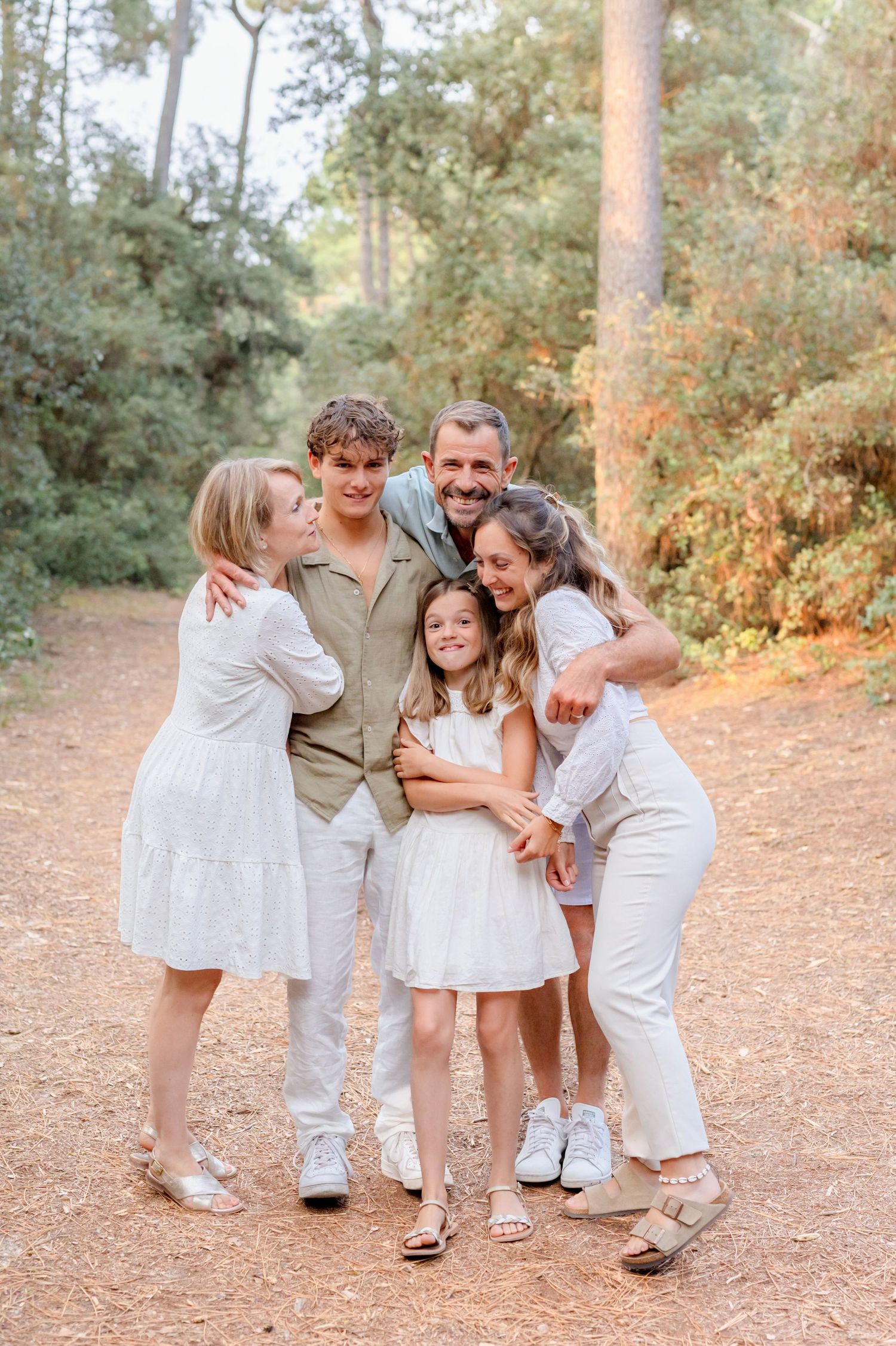 A playful group photo session with everyone wearing coordinated white and beige outfits.