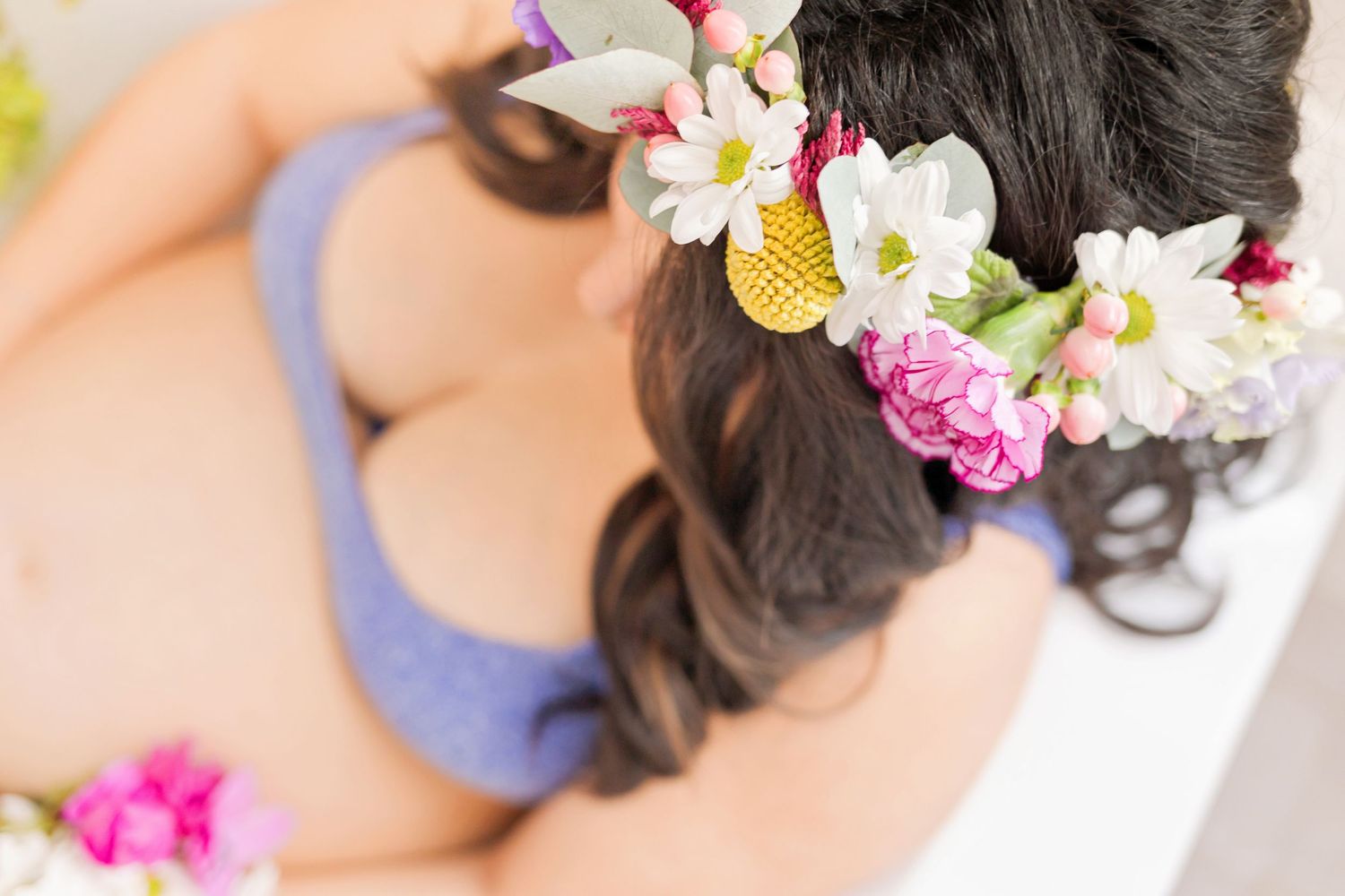 Dreamy portrait with floral crown and delicate flower petals on white background.